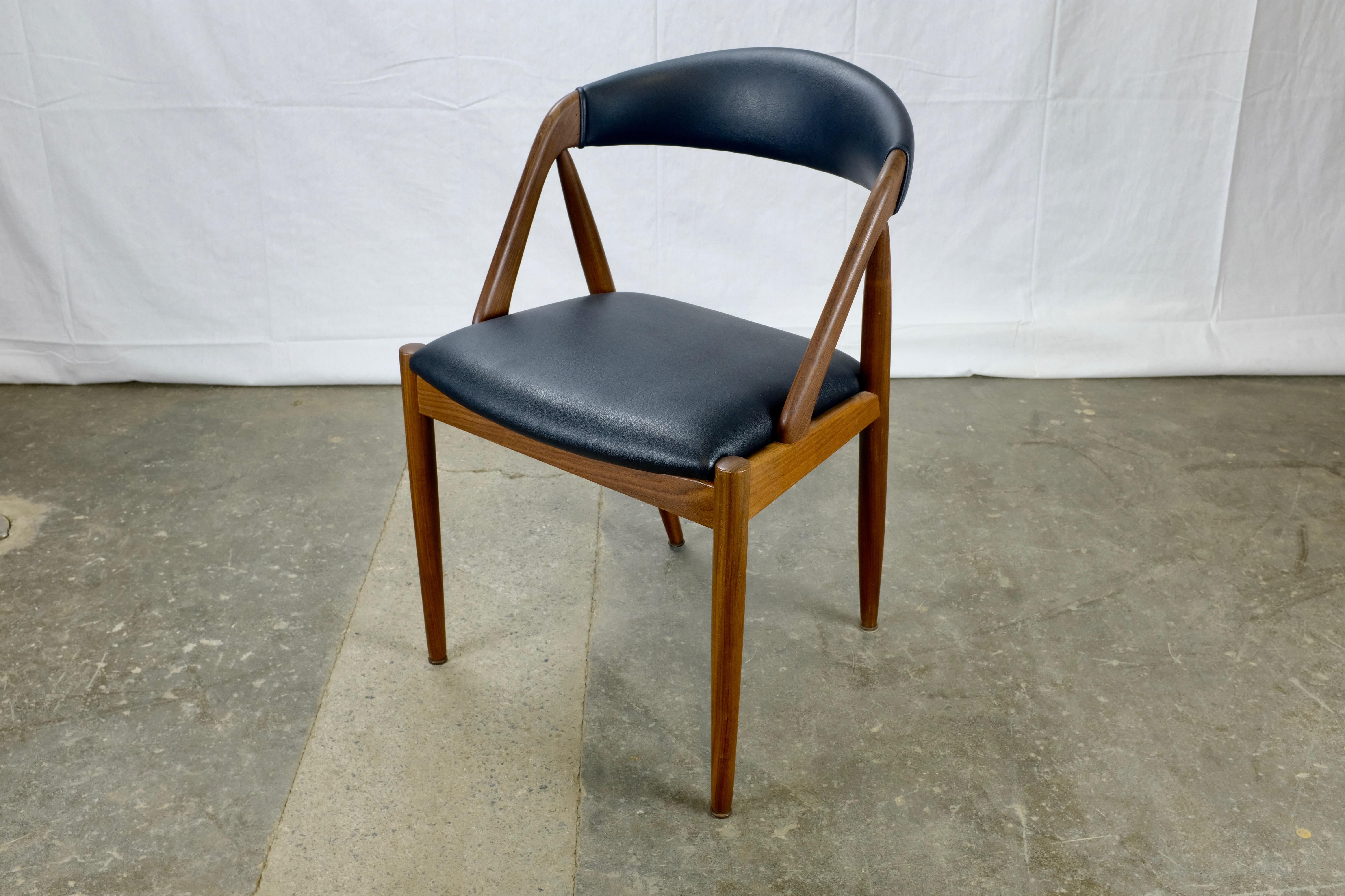 Set of four dining chairs designed by Kai Kristiansen and made in Denmark by Schou Andersen.

The chairs feature distinctive A-shaped frames terminating in gracefully curved backrests.

The solid teak frames have been refinished and the seats
