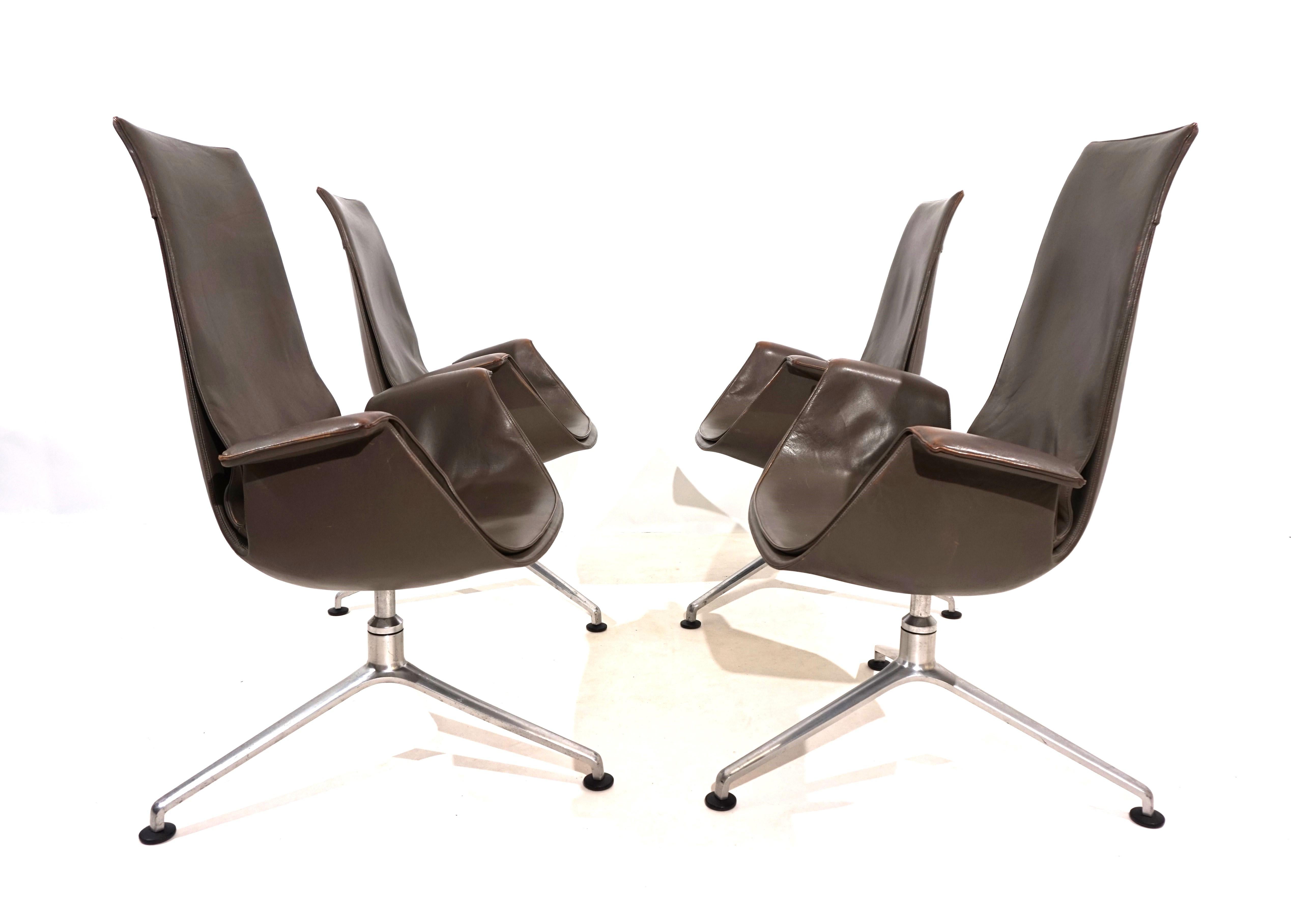 Der Satz von 4 eleganten FK 6725 Bird Stühlen mit hohen Rückenlehnen ist in sehr gutem Zustand. Das taupefarbene Leder der Stühle weist kaum Gebrauchsspuren auf und hat an den Armlehnen eine charmante Patina. Bei einem Stuhl ist das Leder an der