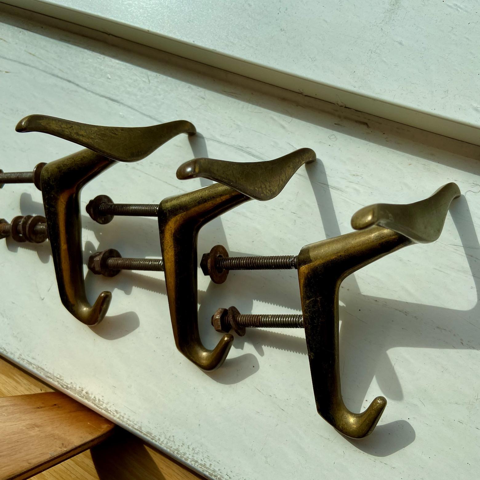 A stylish 1950's set of 4 x triple and 3 smaller double brass hooks or coat hangers in the style of Luigi Caccia Dominioni. 
heavy, sculptural, beautiful design and quality.
the dimensions given are of the large hooks only, without the screws, which
