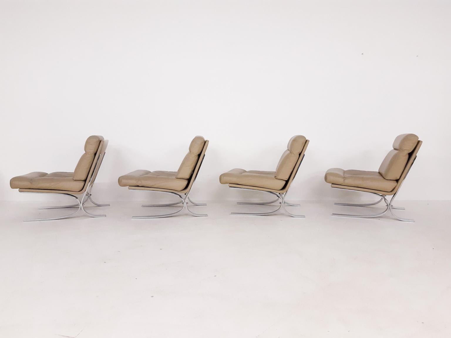 Set of four high quality chromed metal lounge chairs with an off-white or beige leather upholstery.

We think they are designed by Paul Tuttle for Strässle, Switzerland. They chairs are very similar in design to his 