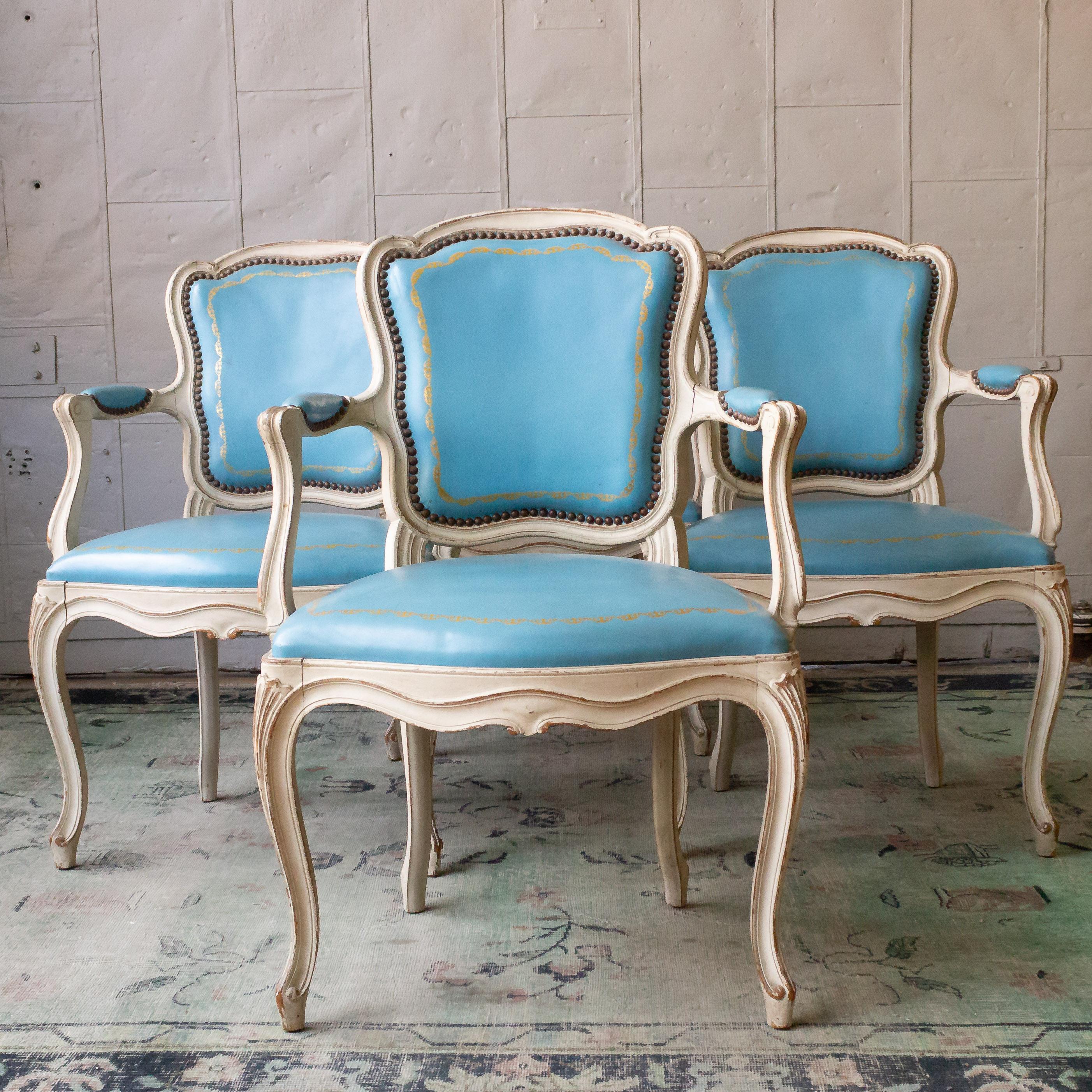 An elegant set of four Louis XV style armchairs in light blue leather and white patinated frames. With this alluring combination of classic French design and rich blue leather upholstery, these chairs are ideal to make a distinctive touch to your