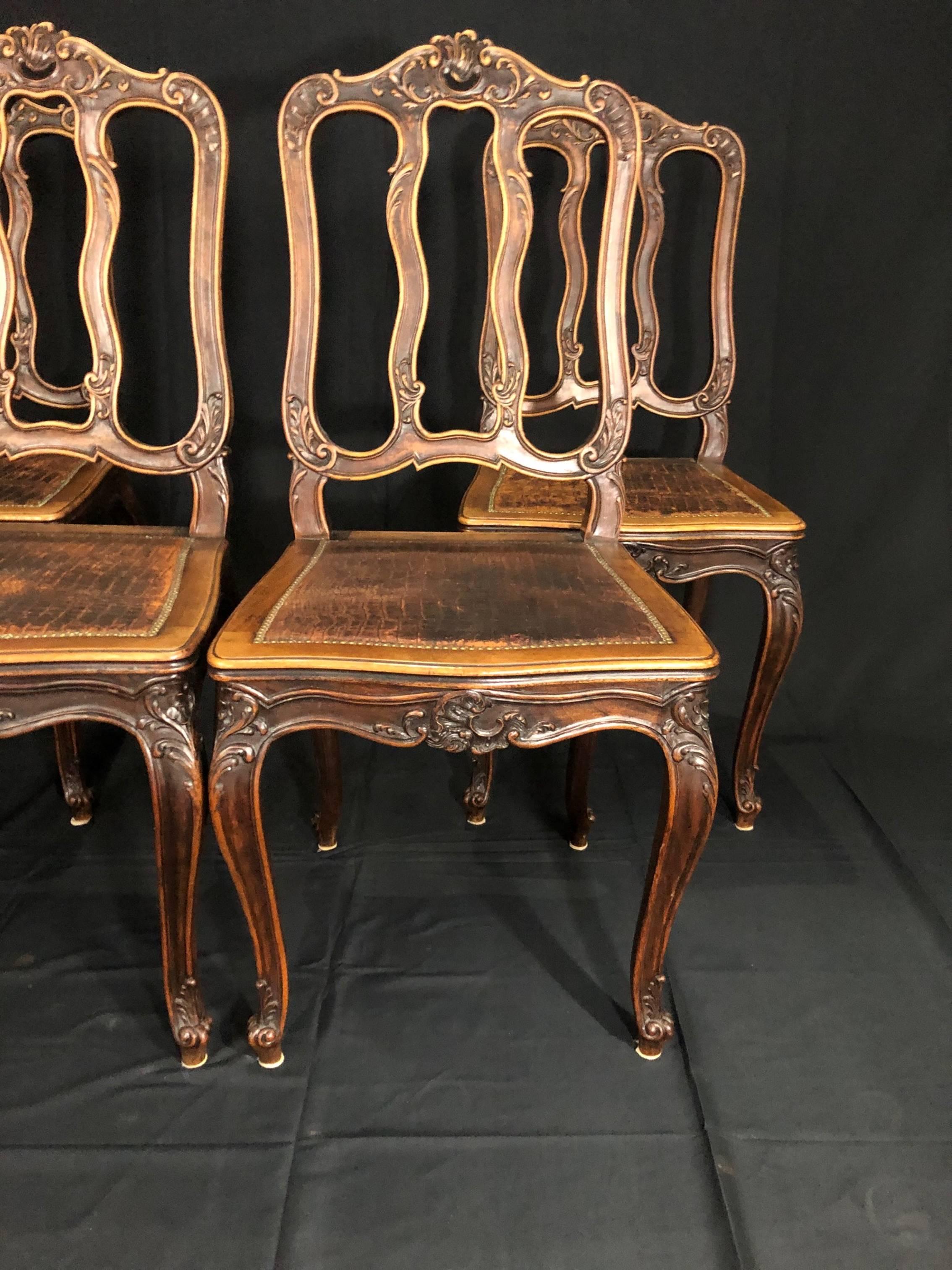 Set of four Louis XV style brown pressed leather carved side chairs having cabriole legs leading to an ornate carved form apron supporting high back rests with wood frames that terminate in acanthus leaf, shell motif and leaf and vine design. All in