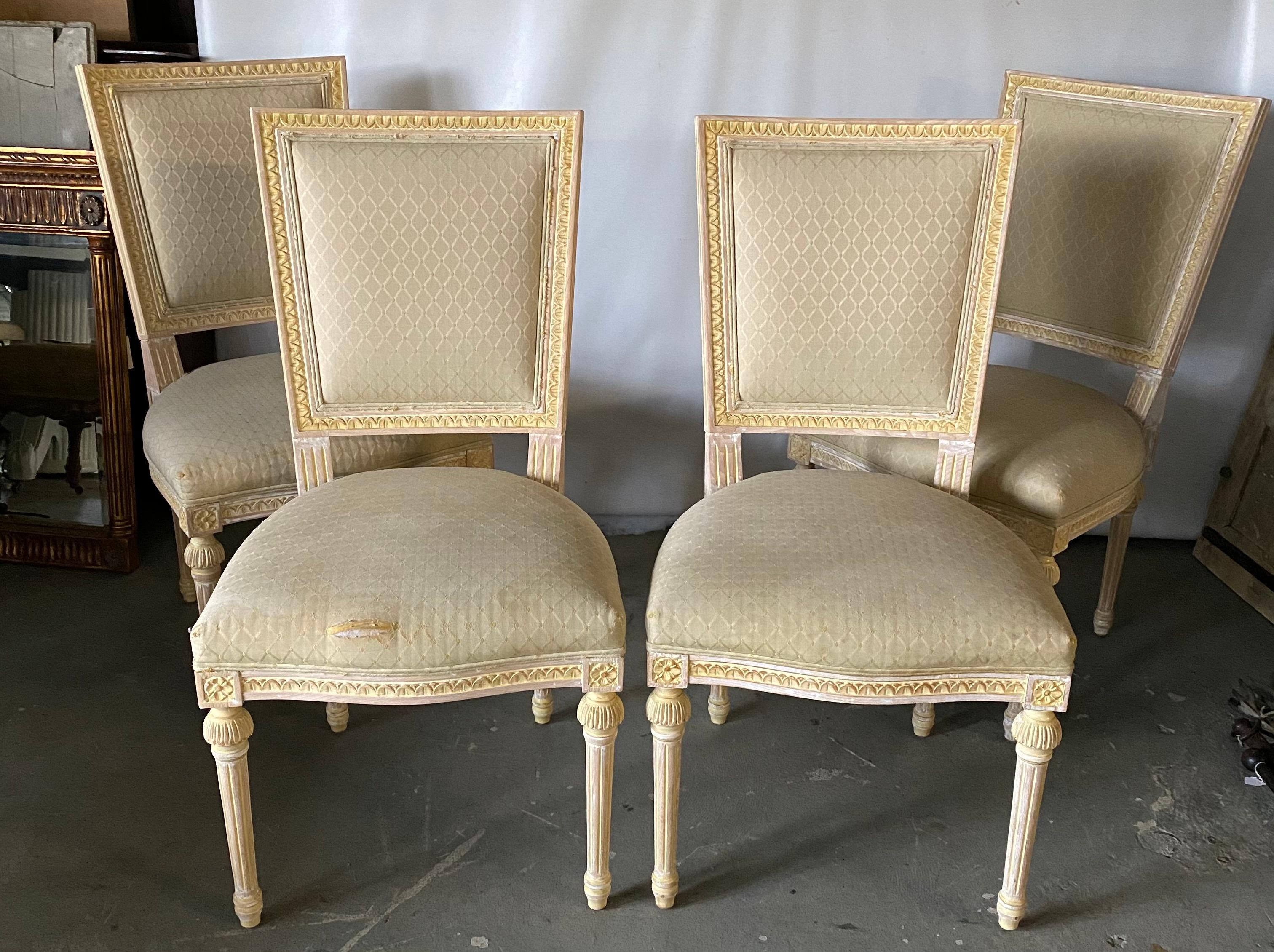 A set of refined and striking Louis XVI style dining side chairs. These beautiful chairs are painted in a soft, creamy white. The chairs have squared upholstered back and seats, fluted, tapered legs characteristic of the Louis XVI style and give
