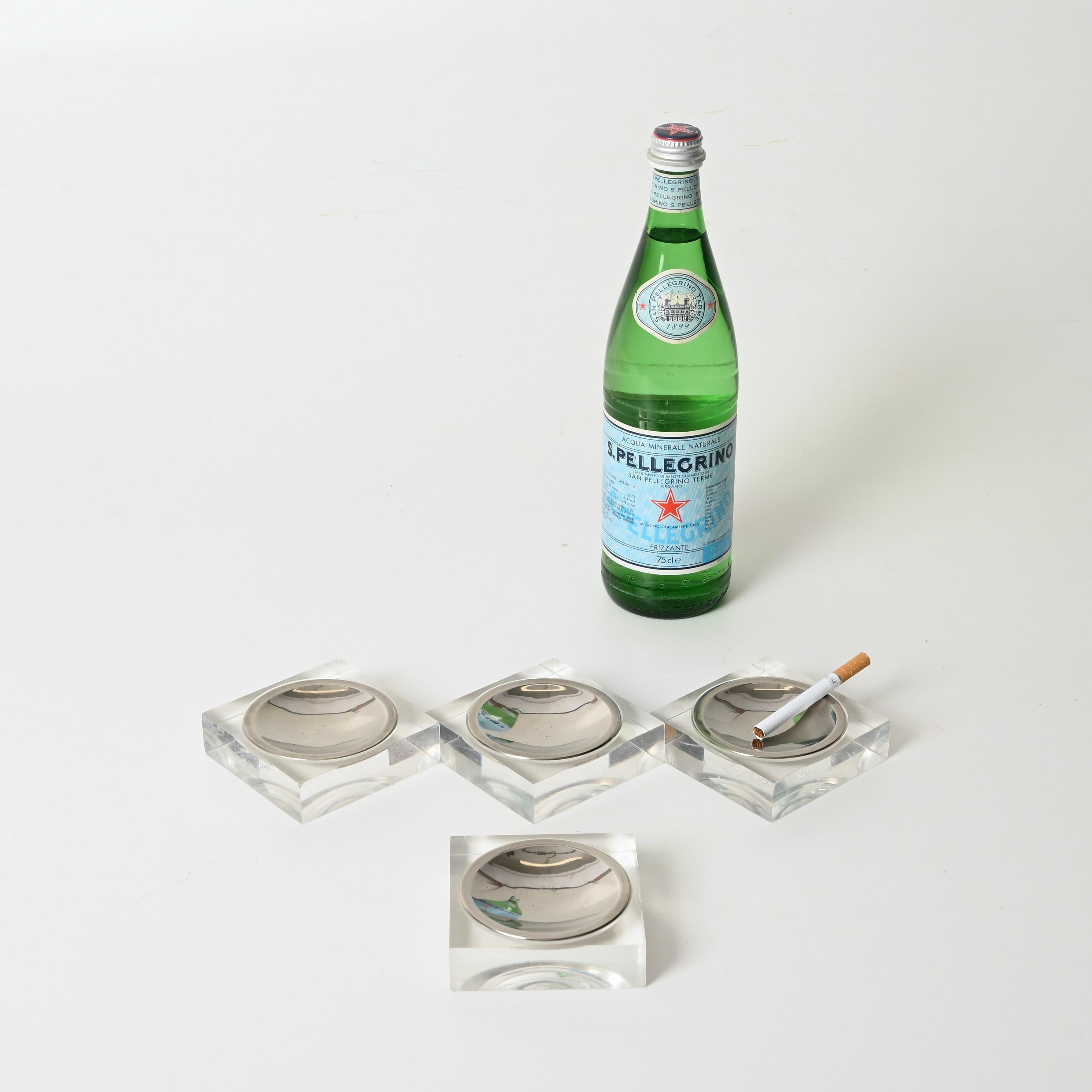 Wonderful set of 4 Mid-Century ashtrays in clear lucite and chrome. These stylish items were designed in France during the 1970s and are attributed to Dior Home production.

In amazing vintage condition. Each ashtray features a square base in clear