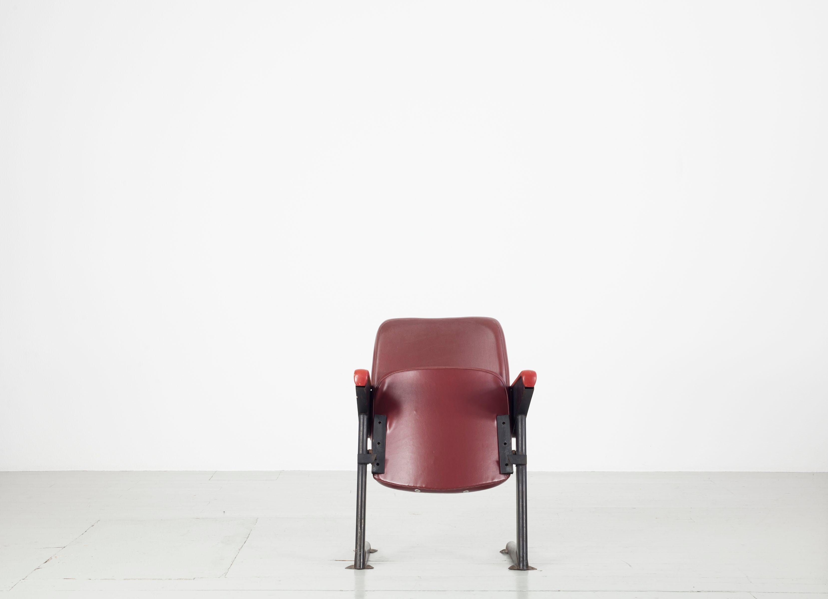 
This set of four LV8 cinema or theatre chairs was made in Padova, Italy by RIMA in the 1950s. The pieces feature faux leather upholstery and fold-out seats. The chairs are in classic red and are supported by a dark iron frame. The entire set is in