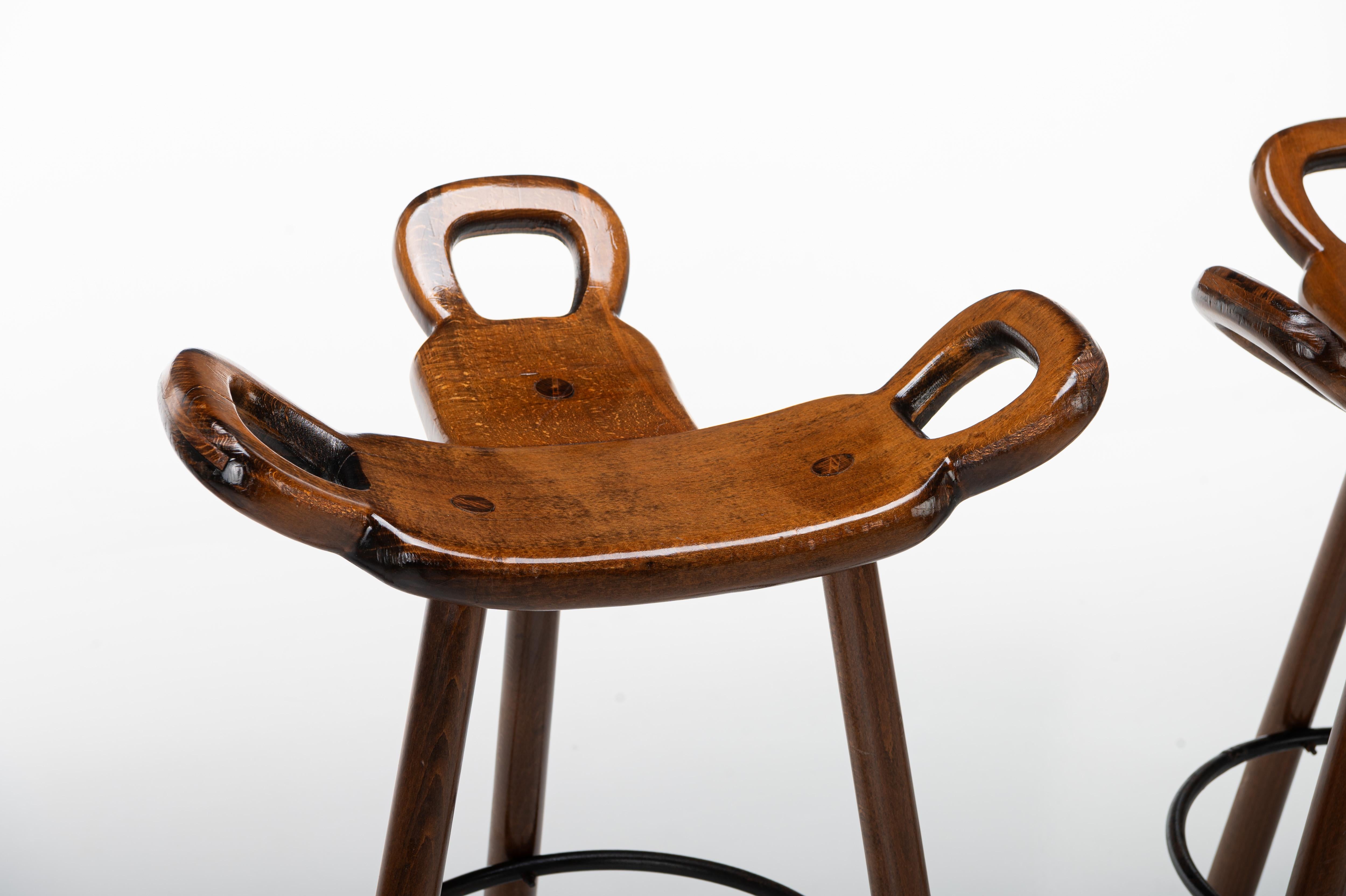 Set of four Spanish vintage bar stools. These 'Marbella' bar stools were produced by Confonorm in Spain in the 1960s. The bar stools are made of wood and have an iron ring to rest your feet on. This set is still in very good vintage