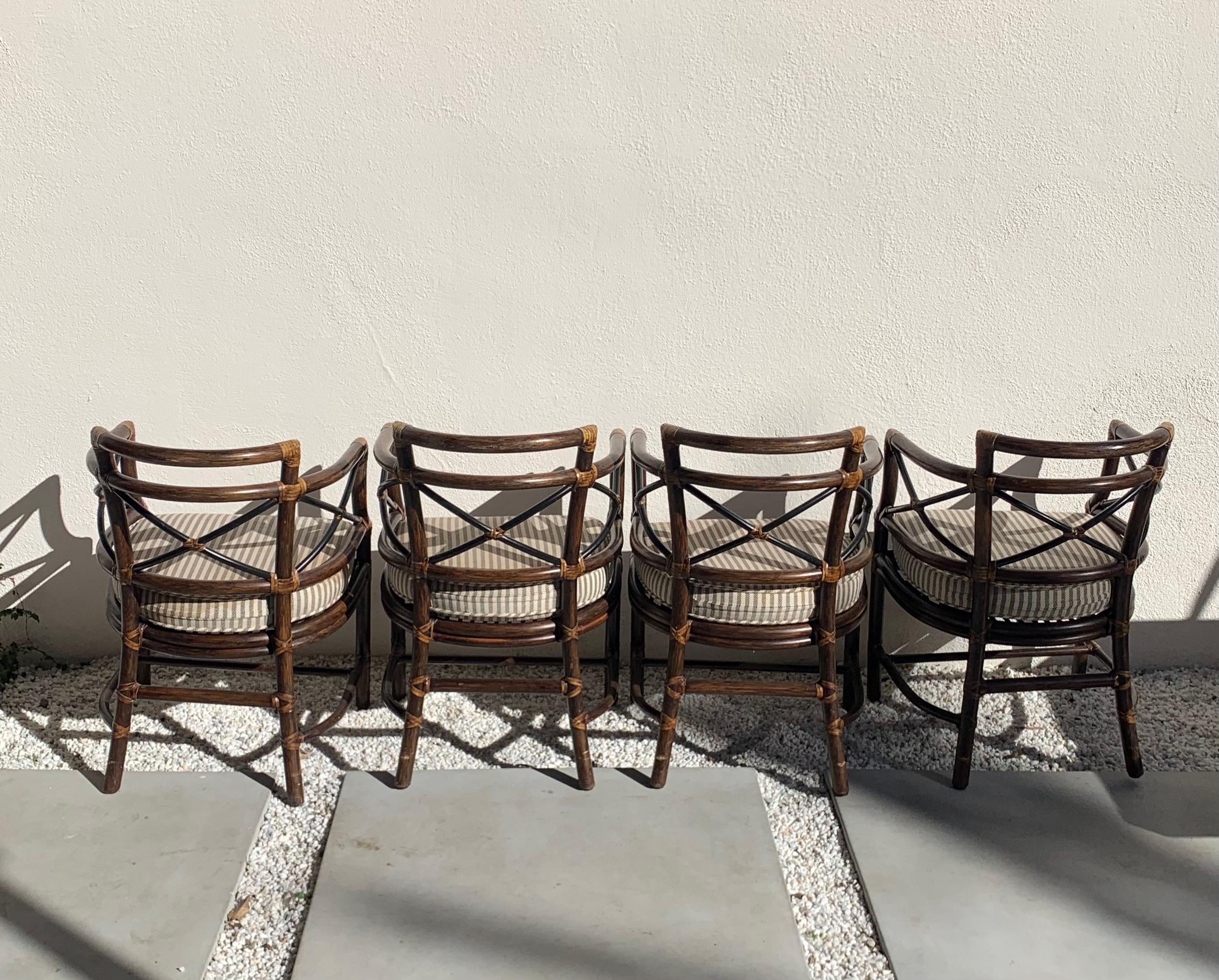 Set of 4 rattan chairs with striped upholstered cushions by McGuire. Made in the Philippines 1960s. Imported via San Francisco. Rattan is in excellent condition; cushions show very minor signs of age - see photos.