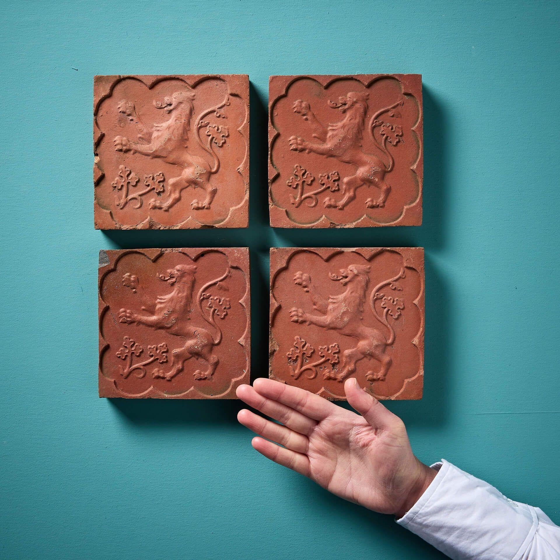 Superbe ensemble de 4 carreaux de terre cuite identiques de style médiéval, décorés de lions rampants en relief et de feuillages dans des bordures festonnées, datant d'environ 1920. Ces carreaux anciens sont d'origine belge ; la marque du fabricant