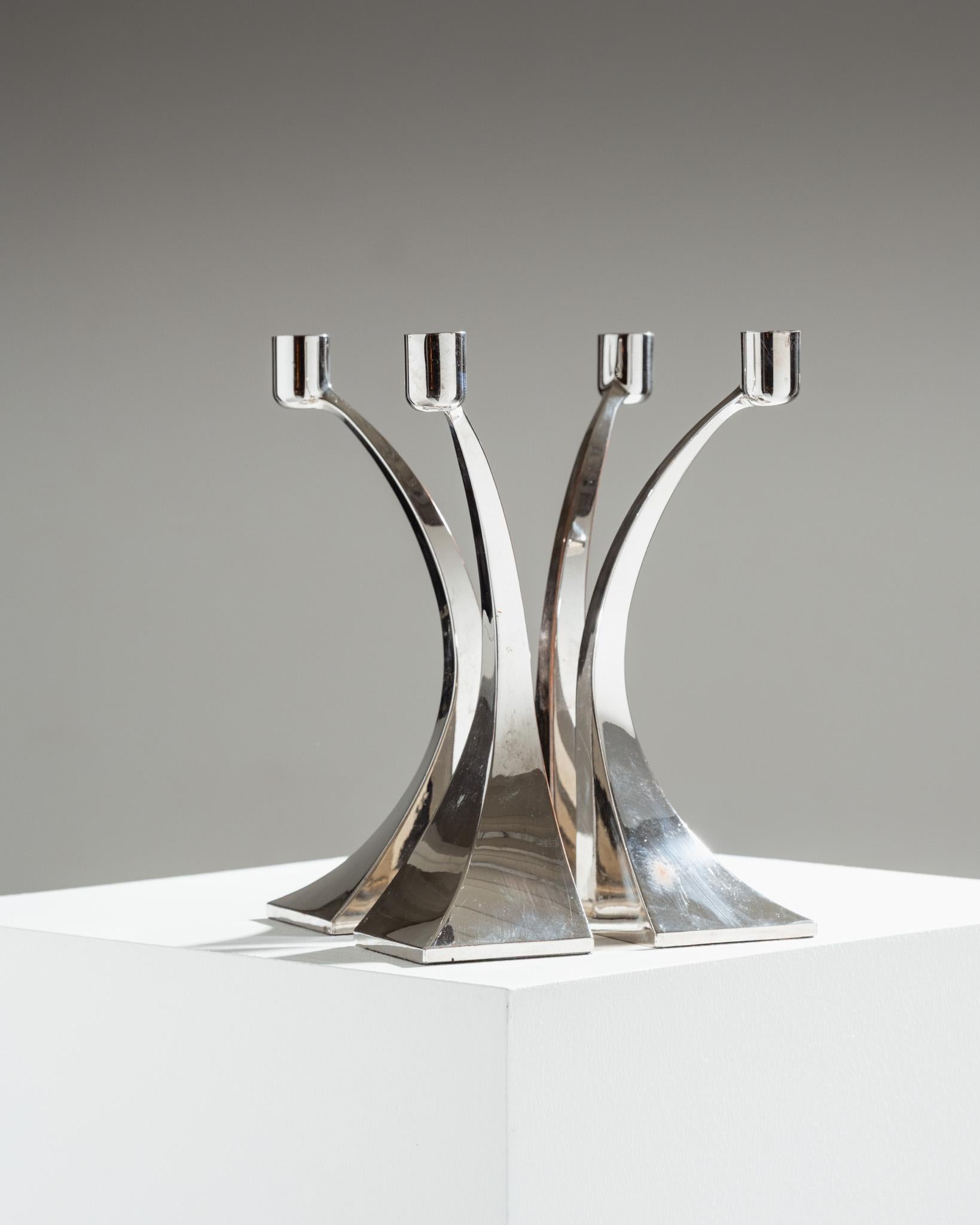 Set of four Italian silver-plated metal candlesticks, 1970s.
Each candlestick rests on a flared square base. Modular design allows them to be used individually or grouped together as a single block. Shows minor signs of wear and oxidation consistent