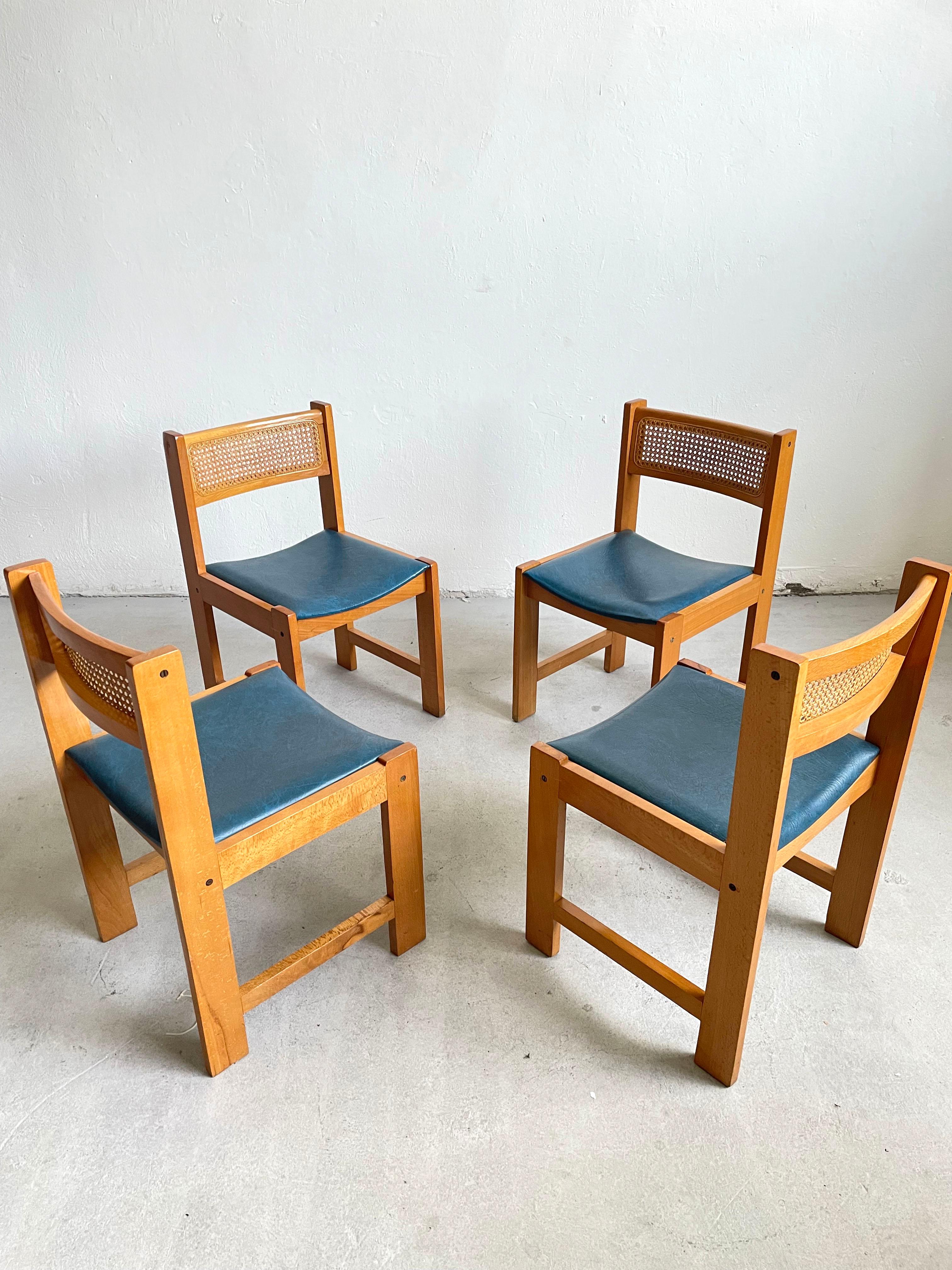 This is a set of 4 vintage dining chairs.

Beautiful vintage mid century wooden dining chair feature blue vinyl seat with dark patches and a cane backrest. They have a very simple and elegant modernist form. 

The chairs have original finish which