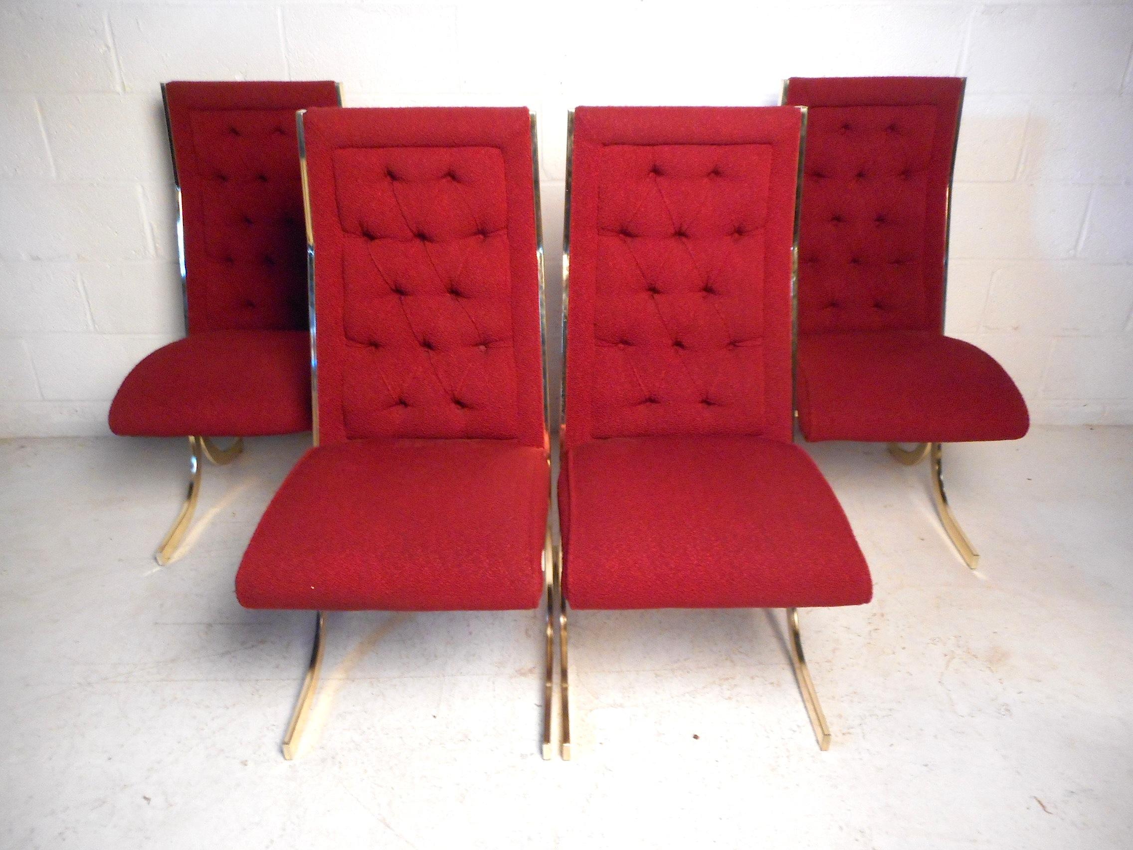 This impressive set of midcentury dining chairs feature beautiful red vintage upholstery covering a tufted backrest and plush seating. The brass-plated base employs an interesting design which enhances the chairs' unique visual profile. An