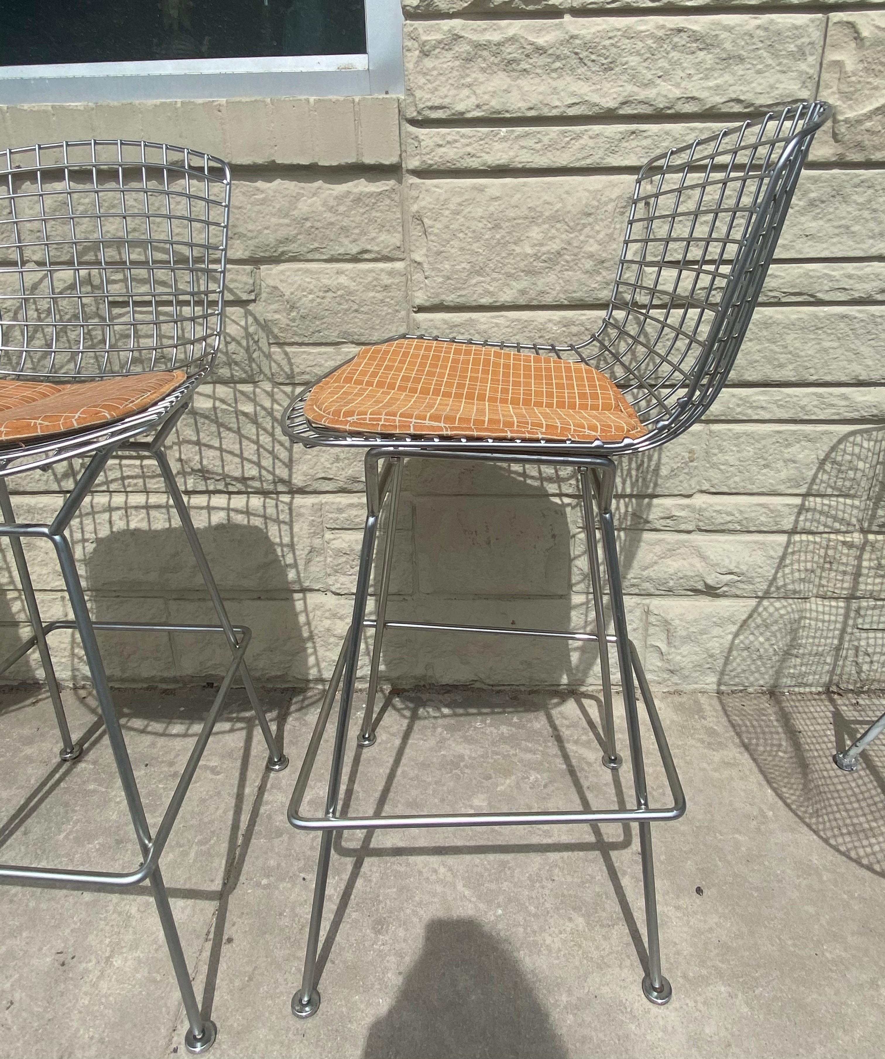 Set of 4 Harry Bertoia Barstools for Knoll in satin chrome. The seat and base are welded steel rods and seat pads snap directly onto the frame. The Bertoia Barstool is part of Harry Bertoia's iconic 1952 wire collection, an astounding study in