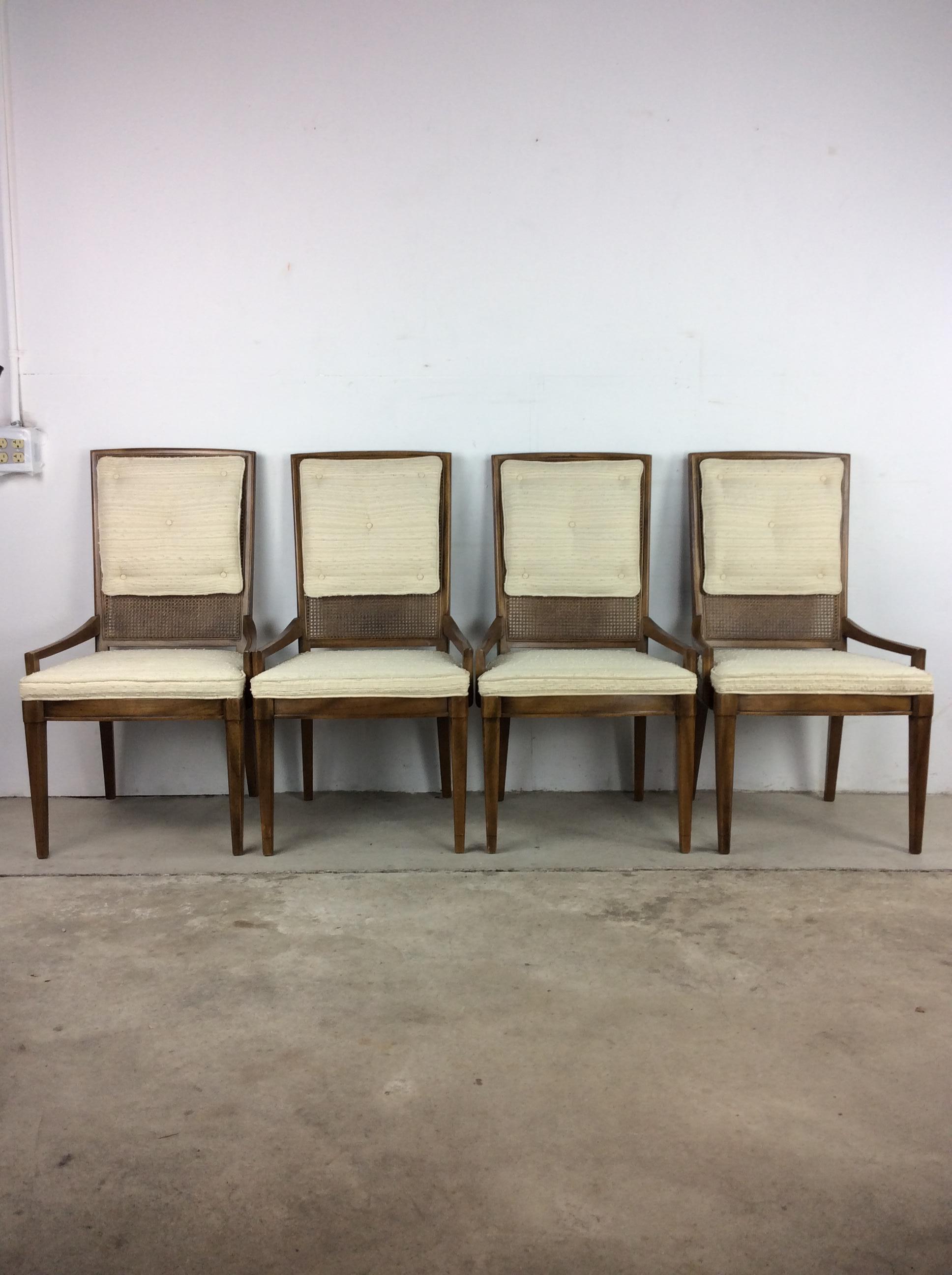 This Mid-Century Modern set of four dining chairs features hardwood construction, unique low arms, vintage white upholstery on seats and back, caning under back cushions, and tall tapered legs.
Dimensions: 21 W 19 D 39.5 H 18 SH 20a H.
 
