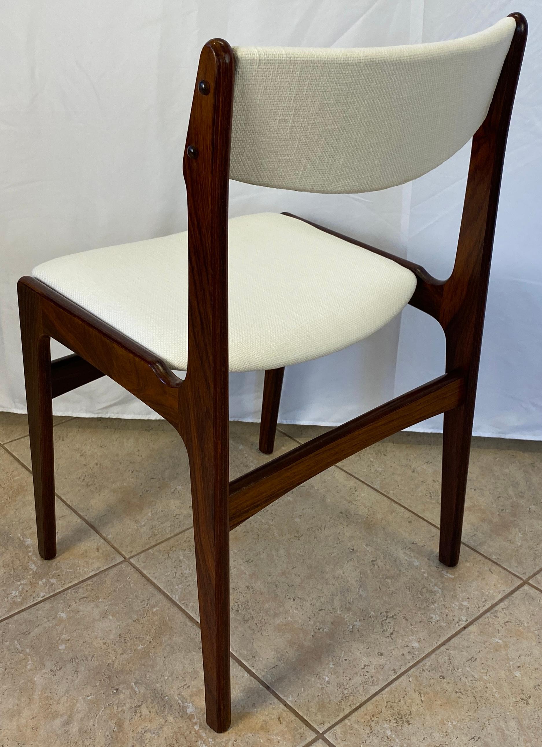 Beautiful set of four modern Danish style dining chairs.  This fine quality set of 4 modern dining chairs were made in Denmark from rosewood known for its elegance and durability. Expertly crafted. Extremely comfortable with new upholstery and
