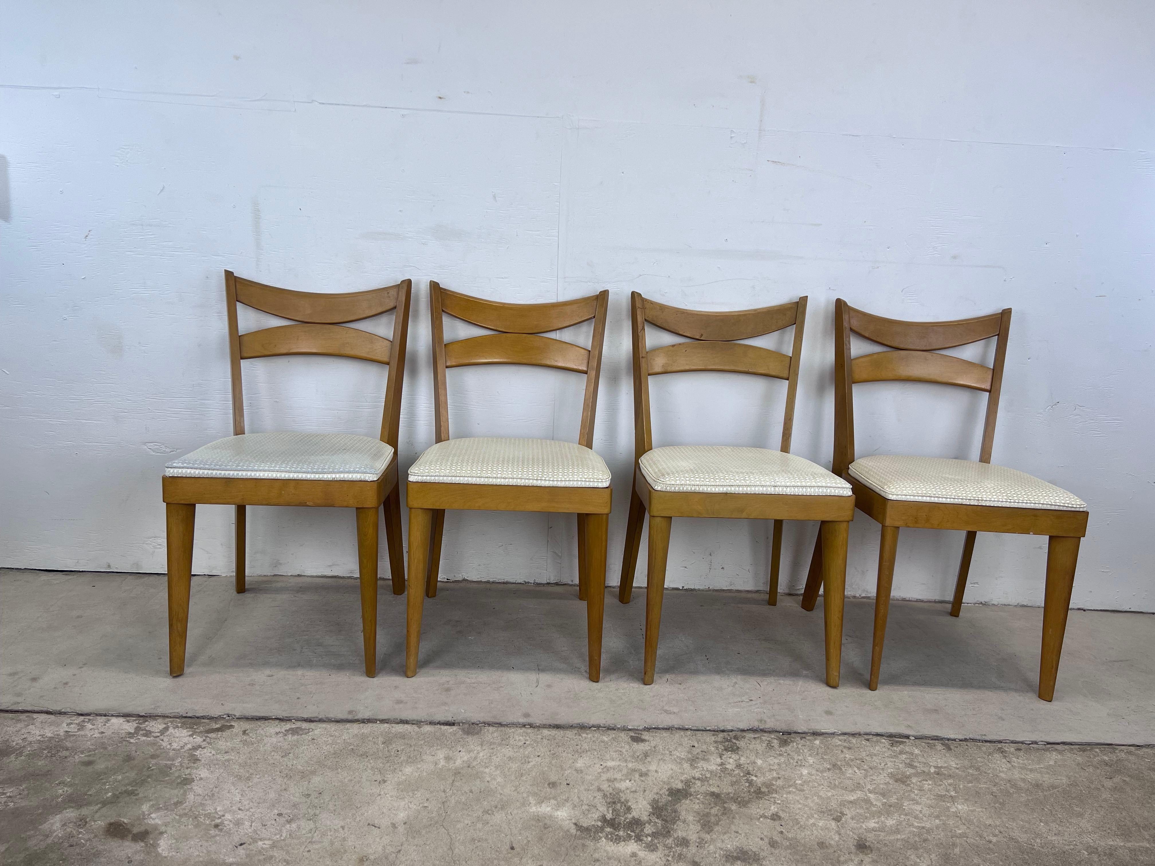 This set of 4 Mid-Century Modern dining chairs by Heywood Wakefield features hardwood construction, original champagne finish, unique bentwood backs, vintage upholstery, and tall tapered legs.


