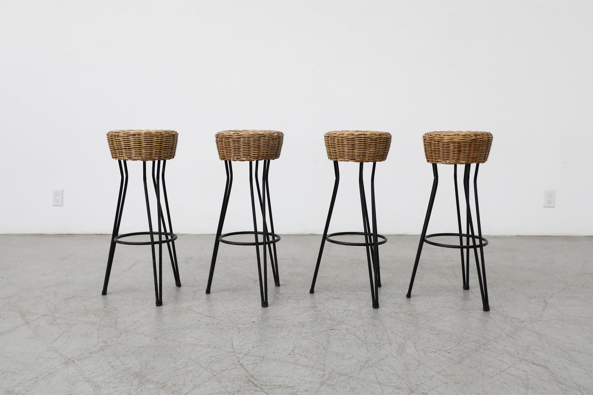 Beautiful set of 4 Dirk Van Sliedregt style bar stools with woven rattan seats and black enameled iron frames with hairpin legs. In original condition with some visible signs of wear consistent with their age and use. Sold as a set of 4. Other