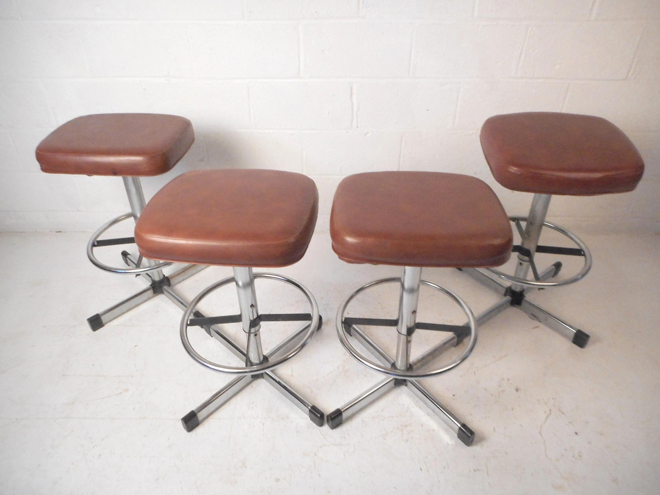 This impressive set of midcentury stools by Samsonite feature comfortable faux-leather upholstered swiveling seats, sleek chrome-plated bases, and sturdy circular footrests. A great addition to any home, business, or office's modern interior, circa