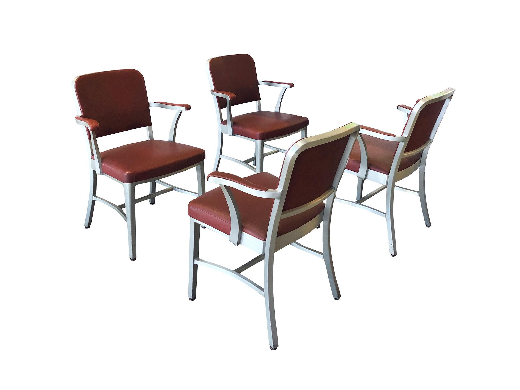 A set of 4 Classic midcentury armchairs manufactured by The General Fireproofing Co. for its line of GoodForm furniture. The chairs are comprised of an aluminum frame and textured vinyl upholstery in a maroon color. The design of these chairs is