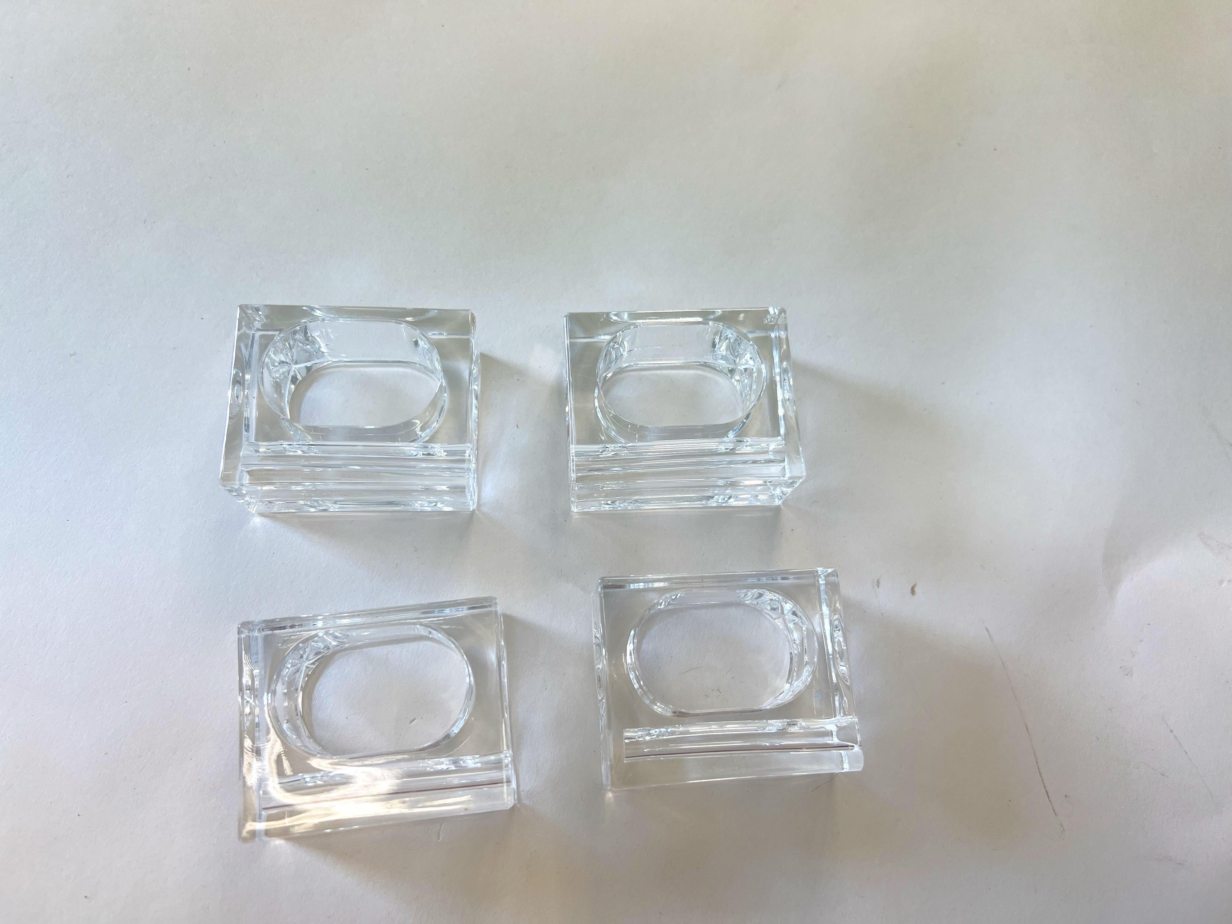Stunning set of four Mid-Century Modern napkin rings or napkin holders with a geometric design. Rendered in polished transparent clear lucite. The design is rectangular in shape on the exterior with an oblong cut out for the napkin on the interior.