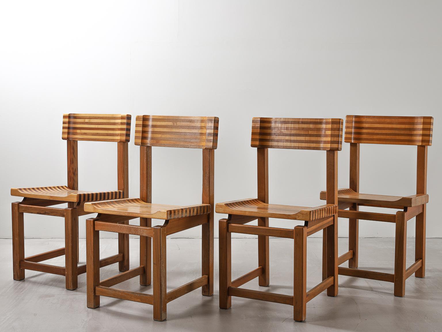 A set of four side or dining chairs, circa mid-20th century, constructed with mid and light toned woods used together to create a striped effect on the seat and backrest in a style reminiscent of the Brazilian artist and furniture designer Joaquim