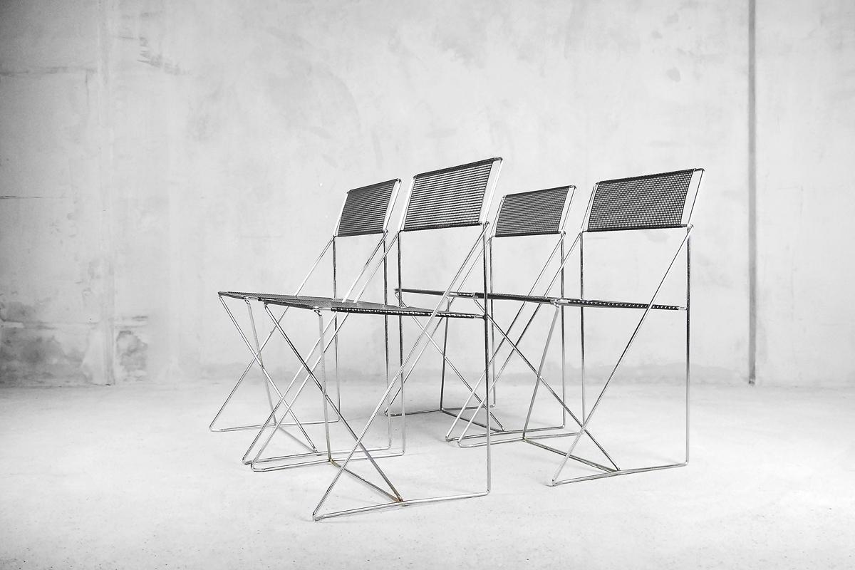 This rare set of four stacking X-line chairs was designed in 1977 by Niels Jørgen Haugesen and produced by Hybodan A/S in Denmark. They are made of chrome-plated steel rods and a black enamelled perforated steel back and seat. This model can be use