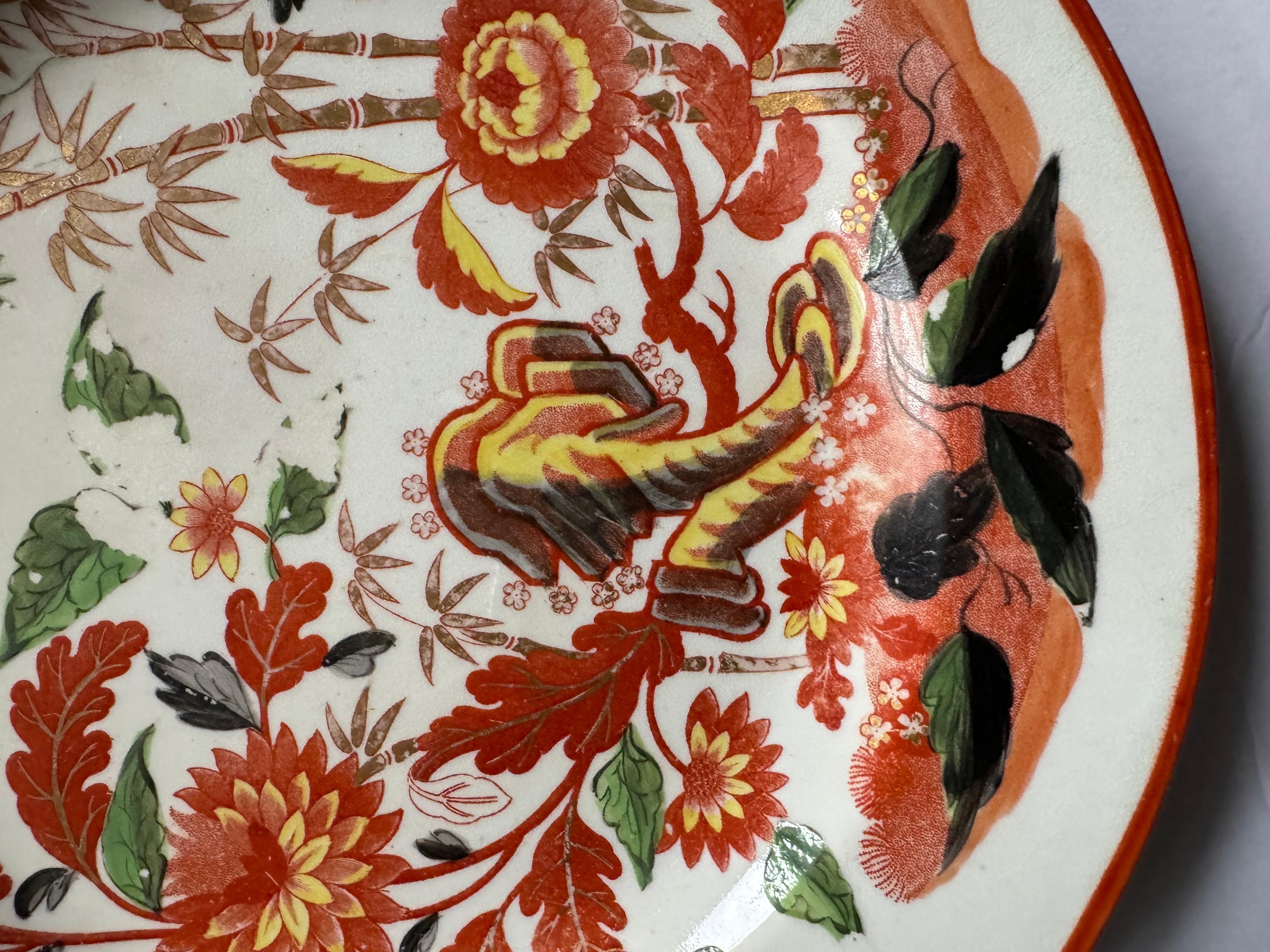 A set of four (4) early Minton porcelain plates, unusually decorated with a red bat-print of Oriental flowers and bamboo branches, overpainted with colorful enamels and complemented by a gilt rim.

Made in England, circa 1806.

Light wear; minor