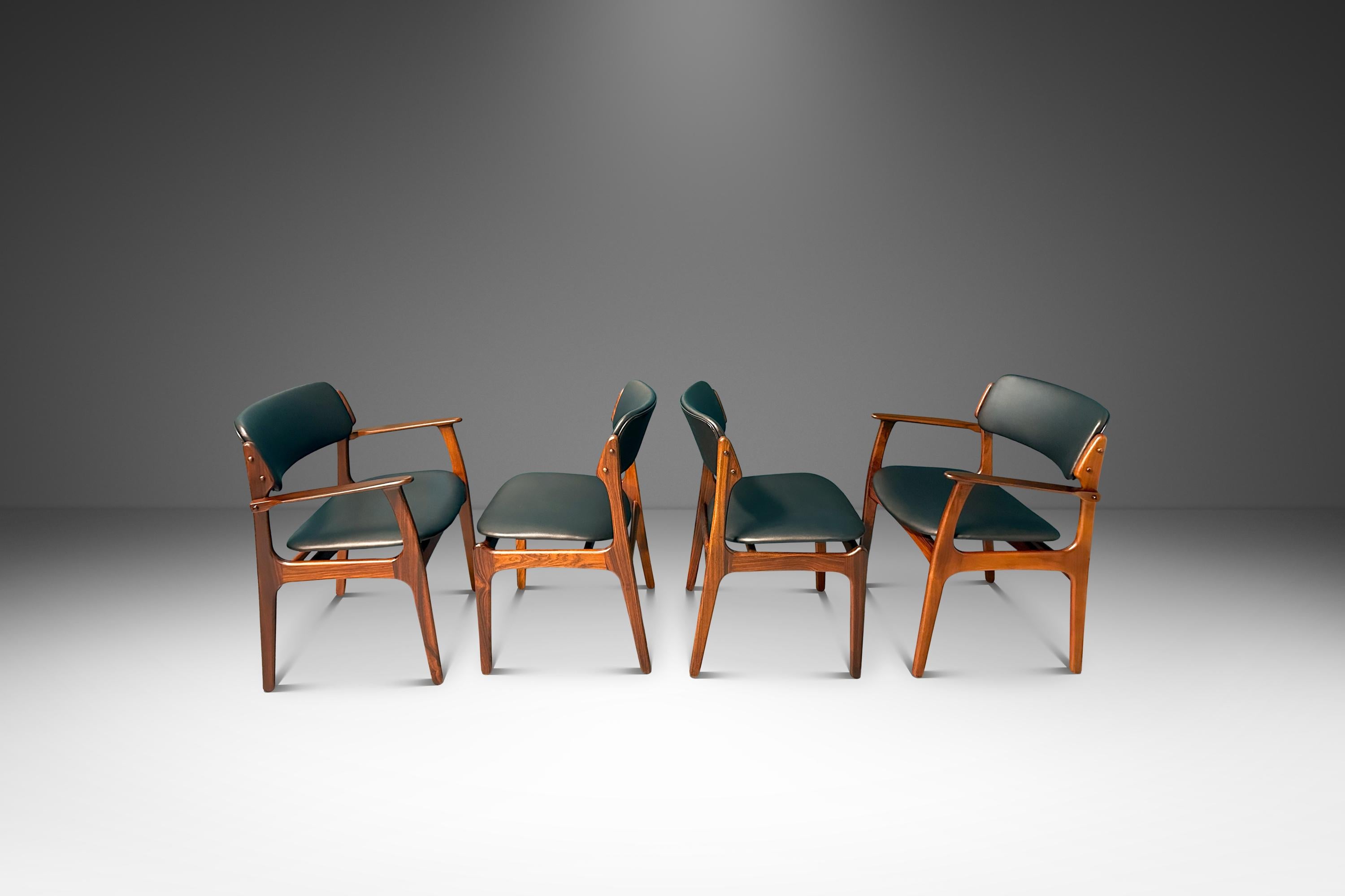  Introducing an ultra-rare set of four vintage Model 49 dining chairs (two armchairs and two side chairs) in solid Brazilian rosewood designed by the influential Erik Buch Oddense Maskinsnedkeri. Recently restored and featuring new vinyl upholstery
