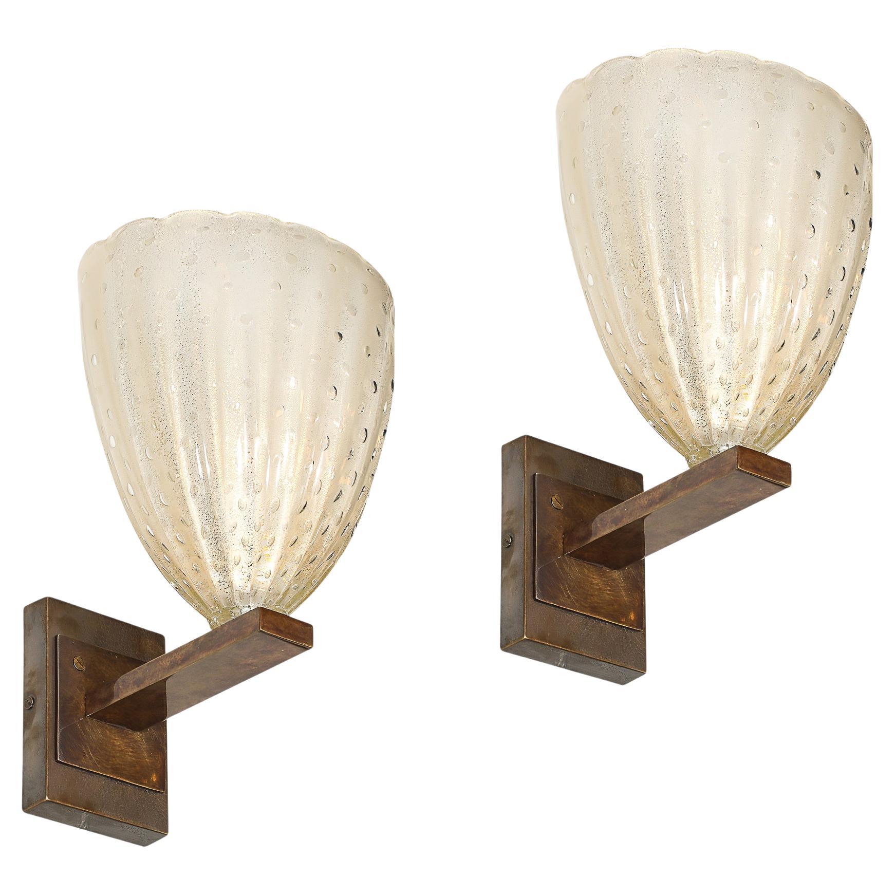 Ce superbe ensemble de quatre appliques modernistes en verre de Murano soufflé à la main, créé en Italie au XXIe siècle, illustre le savoir-faire raffiné et l'allure intemporelle associés à la verrerie vénitienne. Les appliques sont en verre