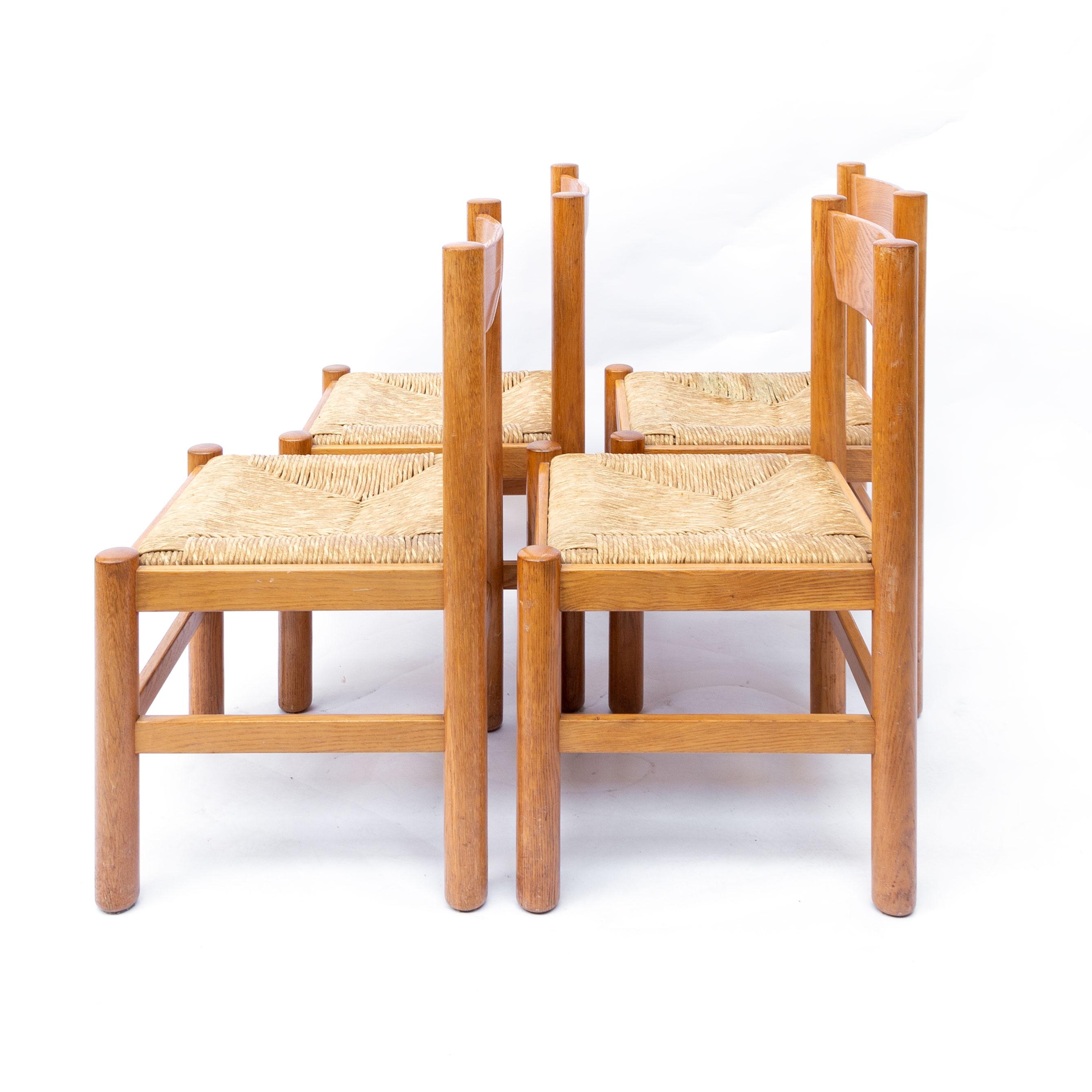 Set of four dining chairs in the style attributed to Vico Magistretti. Wooden frame with rush seatings. Good vintage condition. One seat has a slight stain of usage. The complete set is in good vintage condition. Sold as a set of 4.