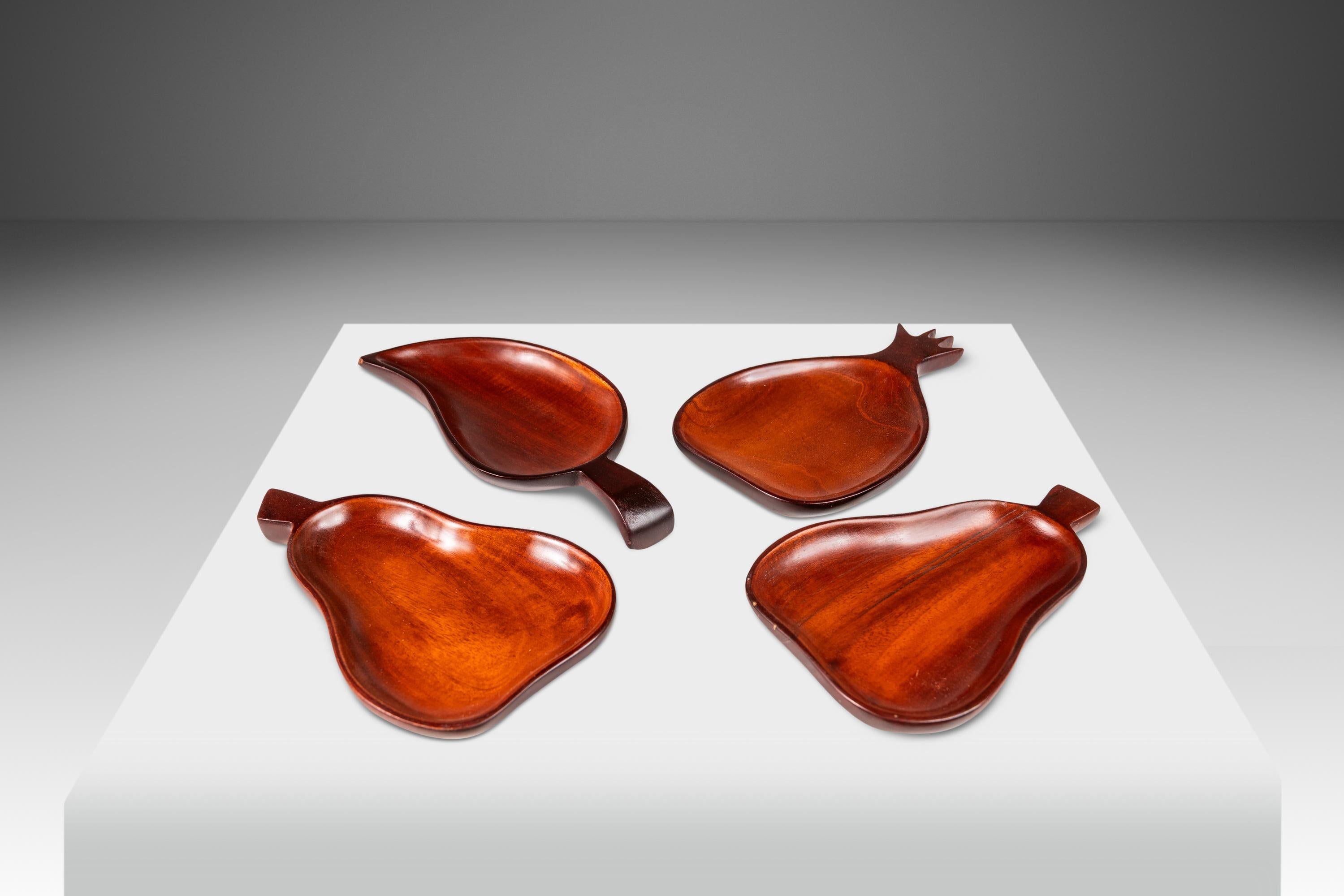  Introducing a set of four hand-carved serving trays. Crafted from solid slabs of solid mahogany, when the rare hardwoods were still plentiful in Haiti, and replete with mesmerizing variegated woodgrains throughout this set features playful shapes