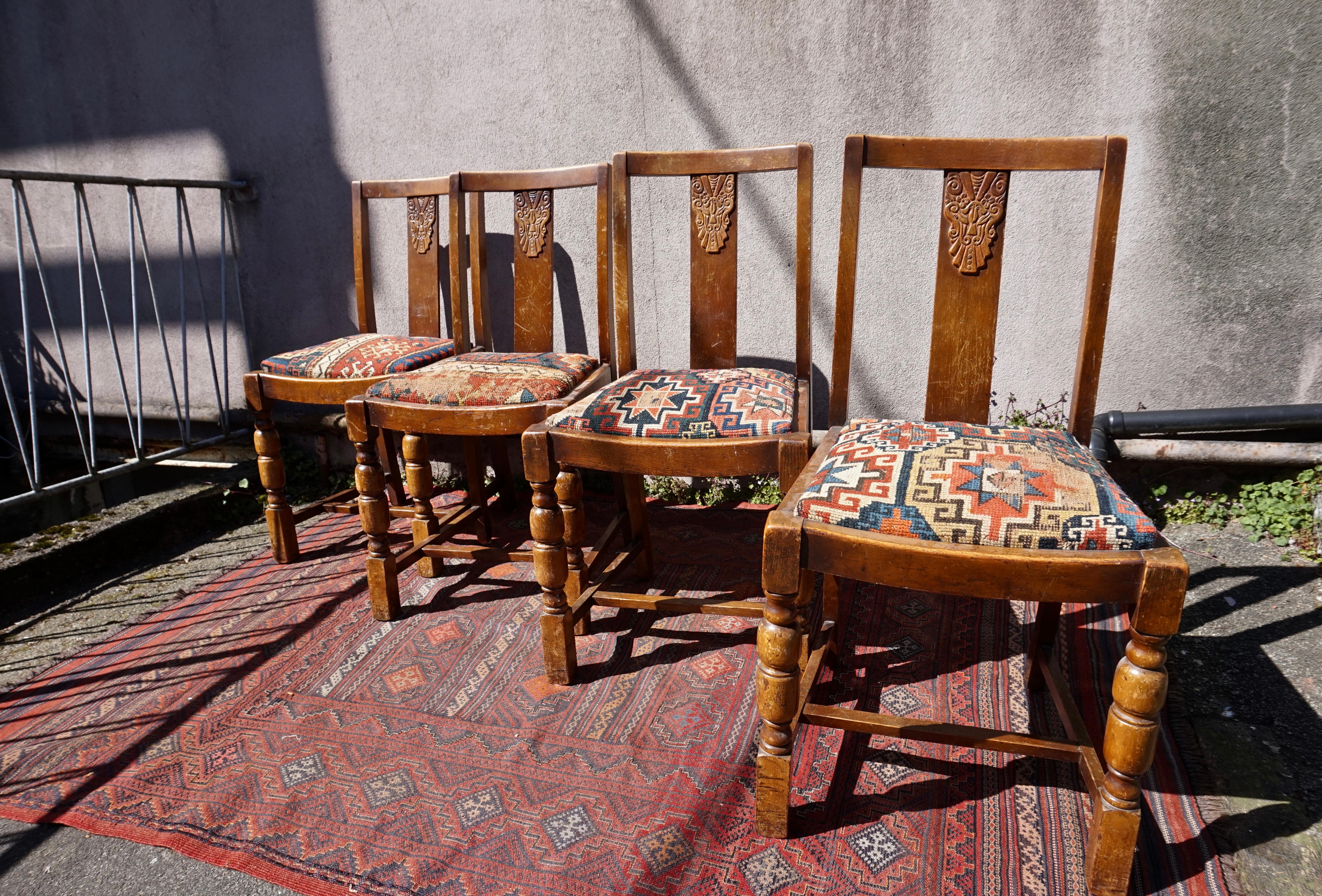 Set of four Art Deco hand carved chairs in original honey patina oak with seats upholstered in rare 19th C. Caucasus rug fragment make this a unique set full of warmth, originality and character. The seats are removable. The chars are sturdy but