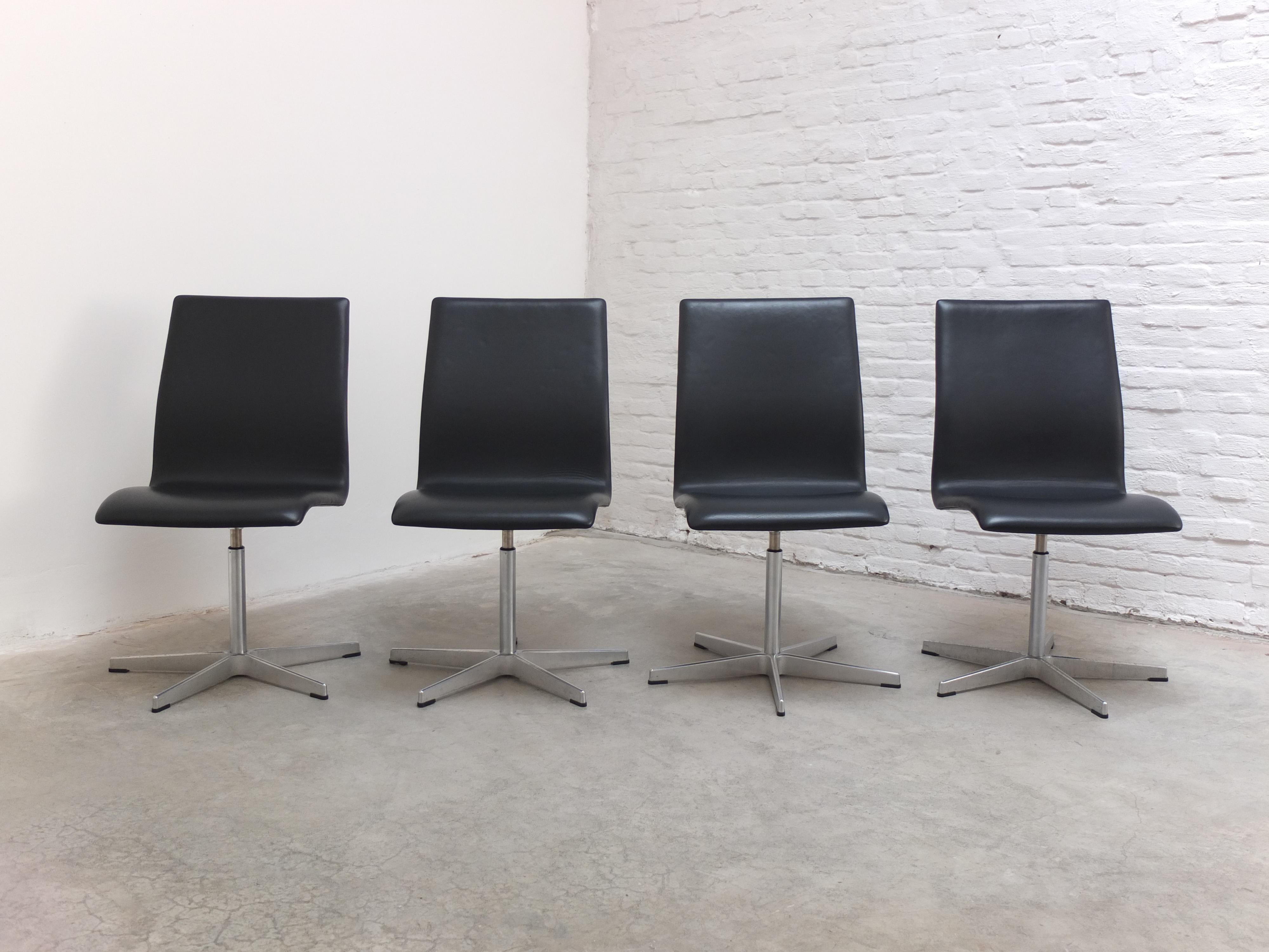 Bel ensemble de 4 chaises pivotantes 'Oxford' conçues par Arne Jacobsen en 1965 pour les professeurs du collège St-Catherine à Oxford. Ces exemplaires sont en cuir noir et possèdent la base en forme d'étoile en aluminium caractéristique de Jacobsen.