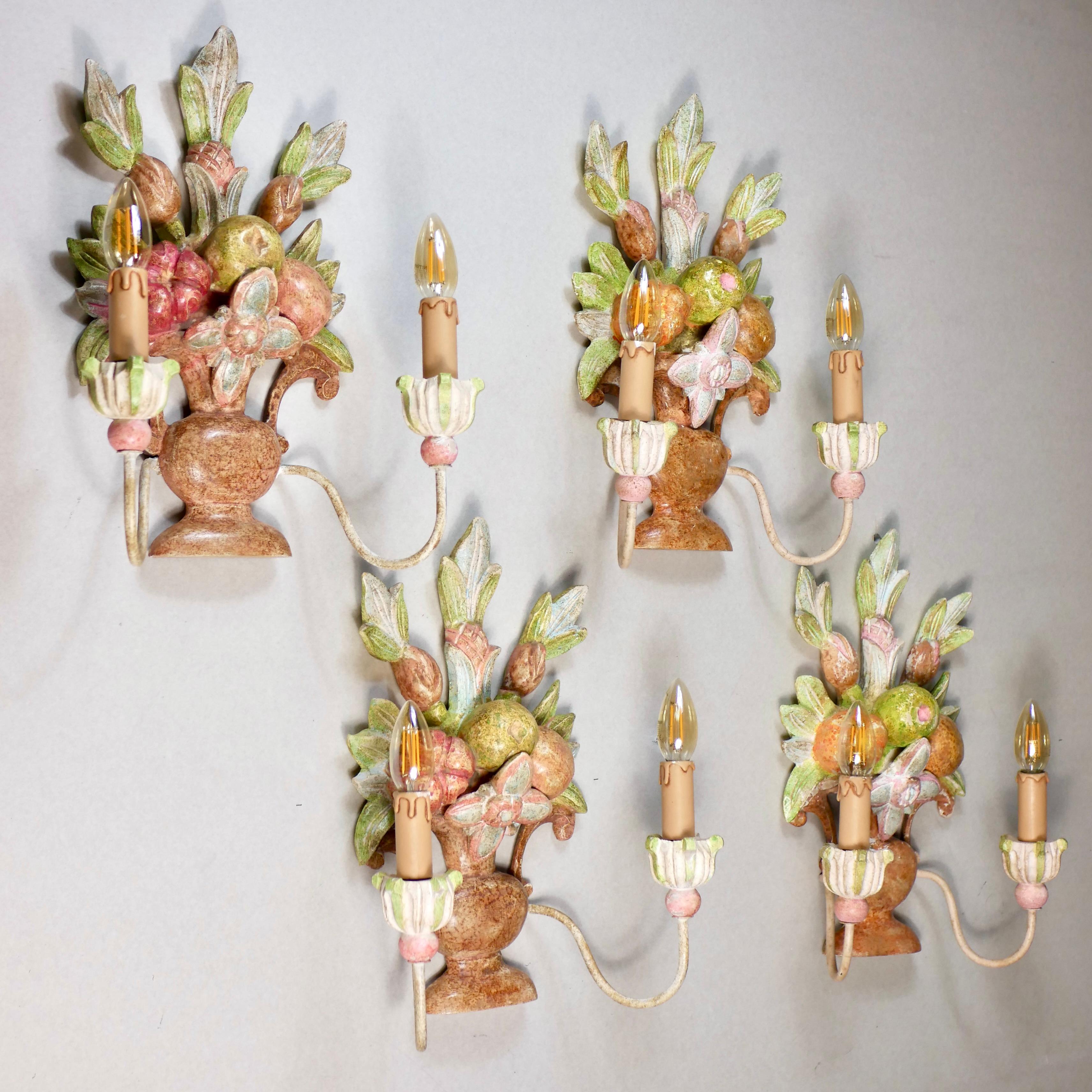 Schöner Satz von 4 handgeschnitzten Holzleuchtern aus Italien aus dem frühen 20. Jahrhundert, die Blumensträuße, Blätter und Früchte darstellen, im Stil von Maison Jansen.
Jede Leuchte ist handbemalt und hat zwei 