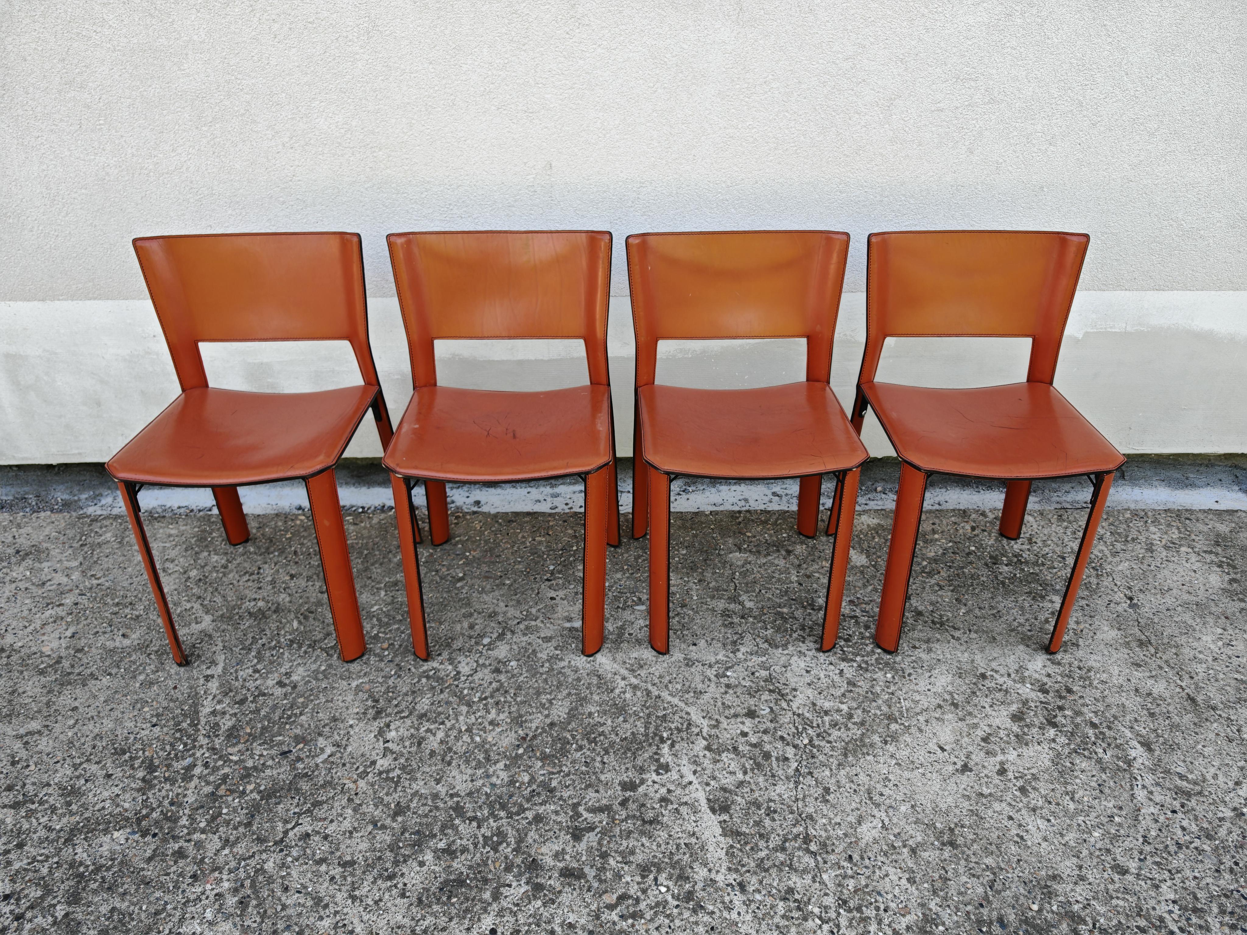 En este anuncio encontrarás un conjunto de 4 sillas de comedor postmodernas, modelo S-91, diseñadas por Giancarlo Vegni para Fasem. Las sillas son de piel de silla de montar color coñac, con un diseño minimalista y líneas elegantes. Cada silla tiene