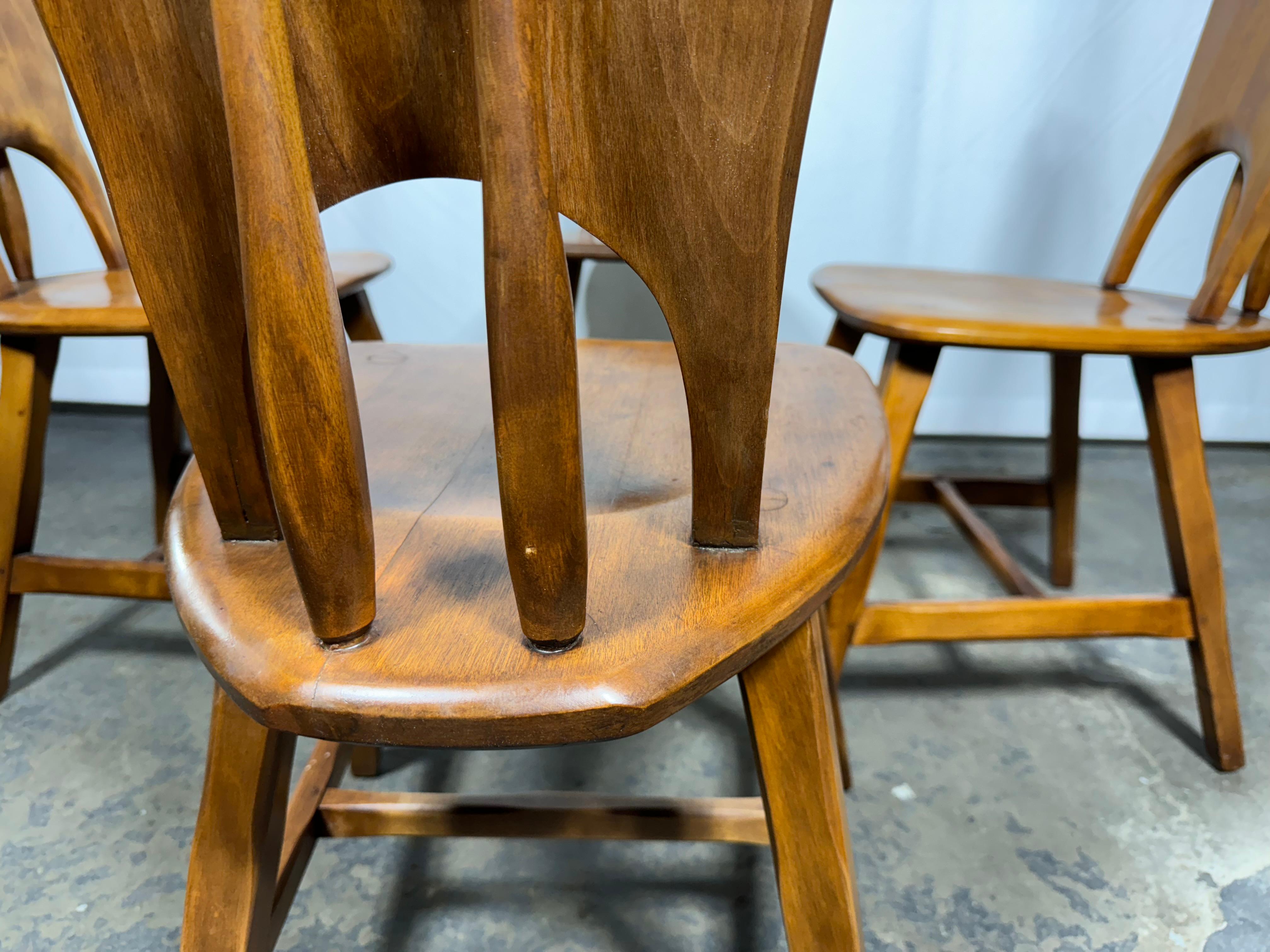 A set of FOUR  American rustic side chairs crafted in hard rock maple. Their distinctive russet finish and chamfered wagon spoke legs are reminiscent of the early to mid 20th century designs of Cushman in Vermont or Wylie R. Dallas of Texas but we