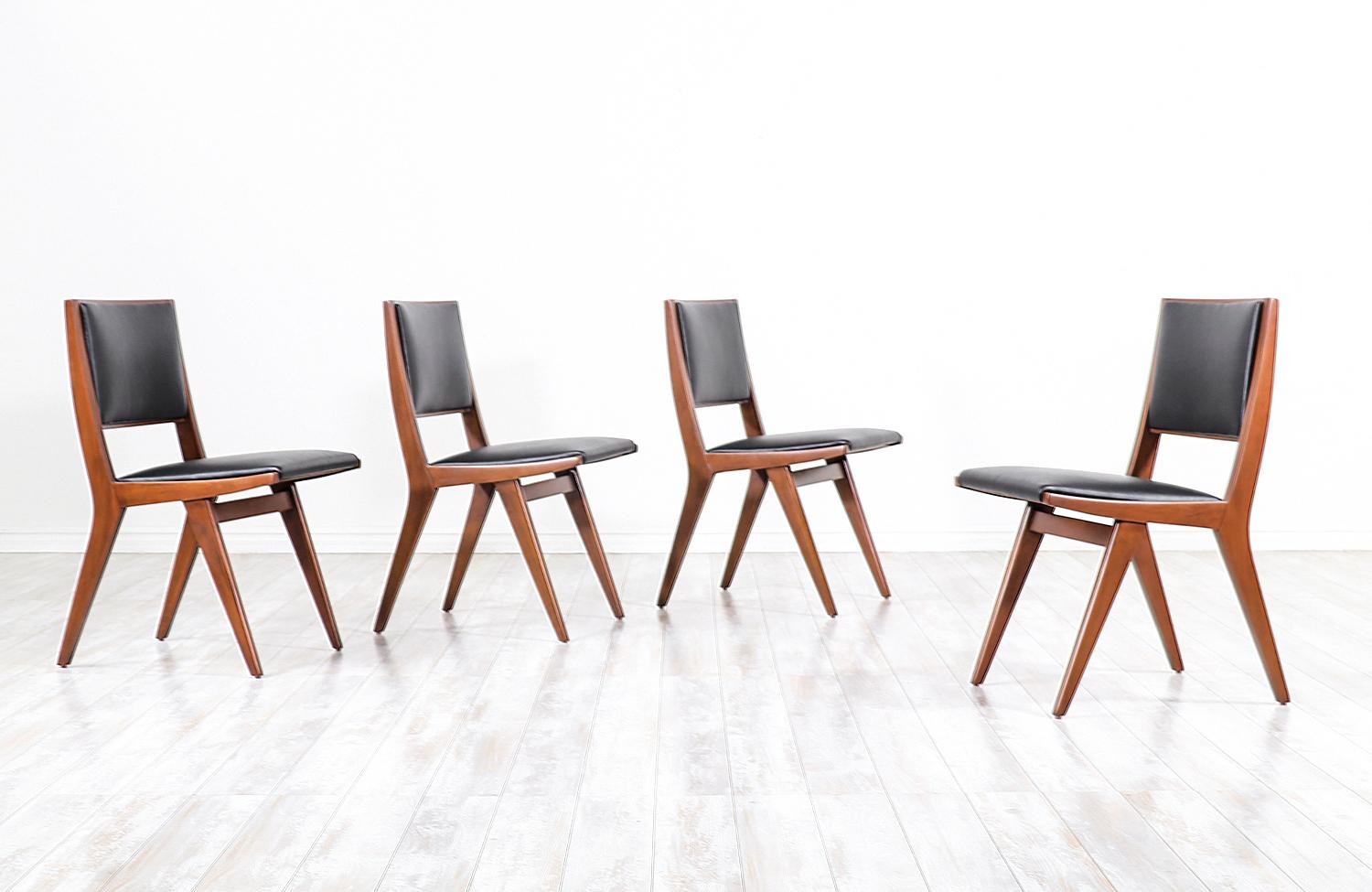A stylish set of four modern dining chairs designed by Dan Johnson for Hayden Hall Furniture in the United States, circa 1940s. This rare and sleek dining set features sturdy walnut-stained beech-wood frames with new high-density foam and top grain