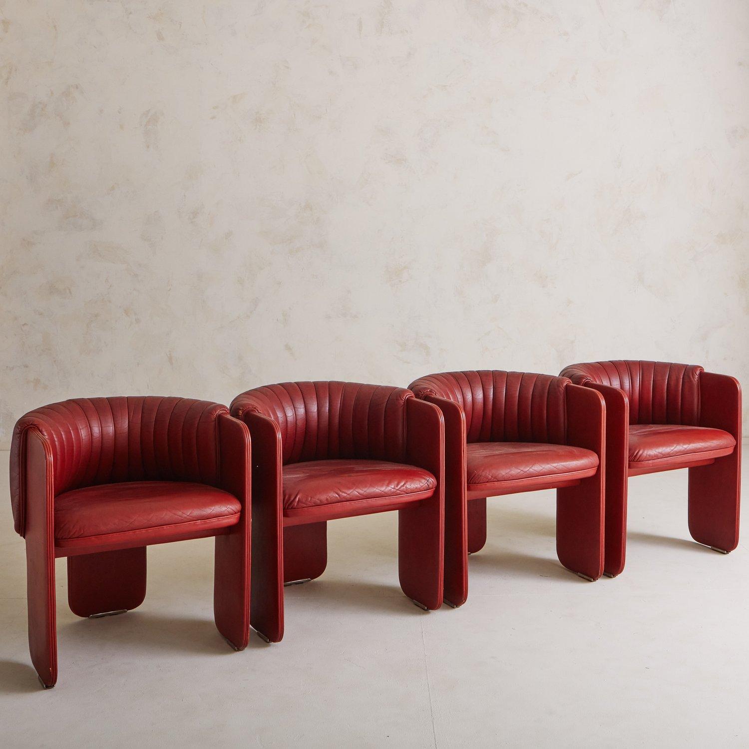 A set of 4 red vegan leather accent chairs by Luigi Massoni for Poltrona Frau, Italy 1980s. These rare three-legged chairs feature elegant curvature and make the most of negative space, offering a remarkable perspective from every angle. We love the