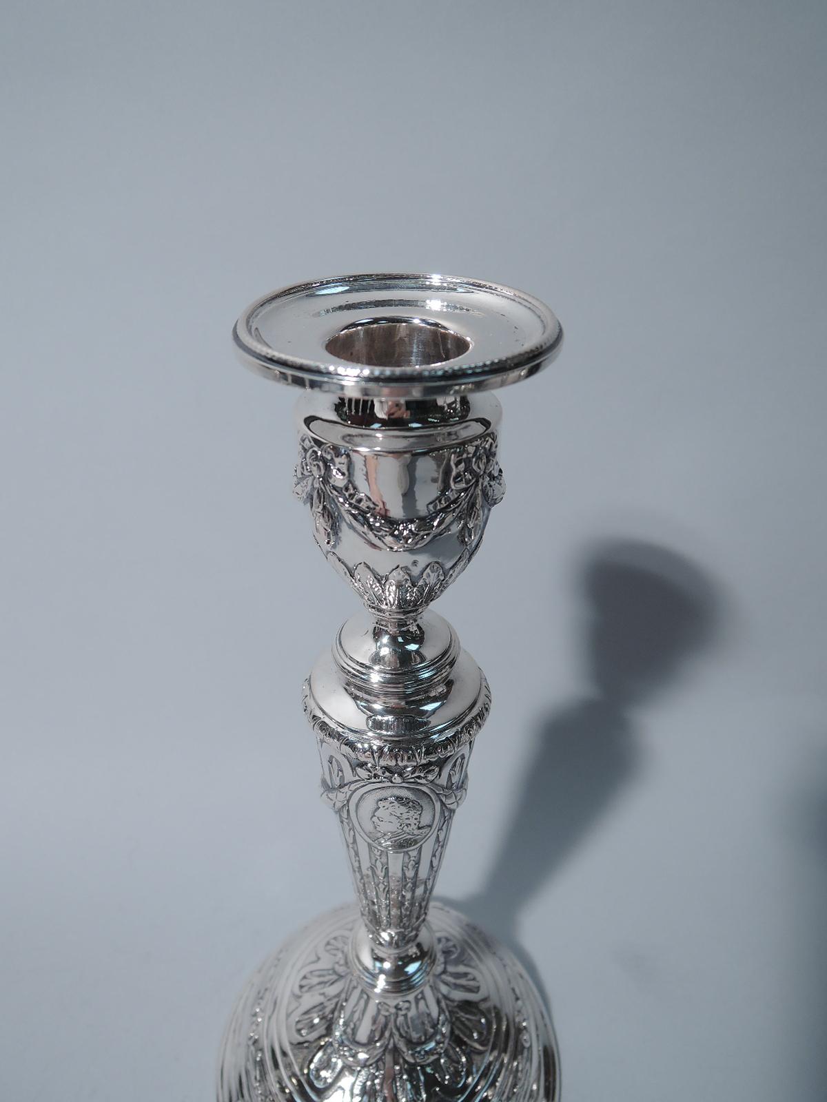 Set of 4 German 800 silver candlesticks, circa 1900. Each: tapering columnar shaft on knopped and domed foot. Urn socket with detachable bobeche. Raised ornament: gadroons inset with stylized flowers, foliage, bow-tied swags, and frames with