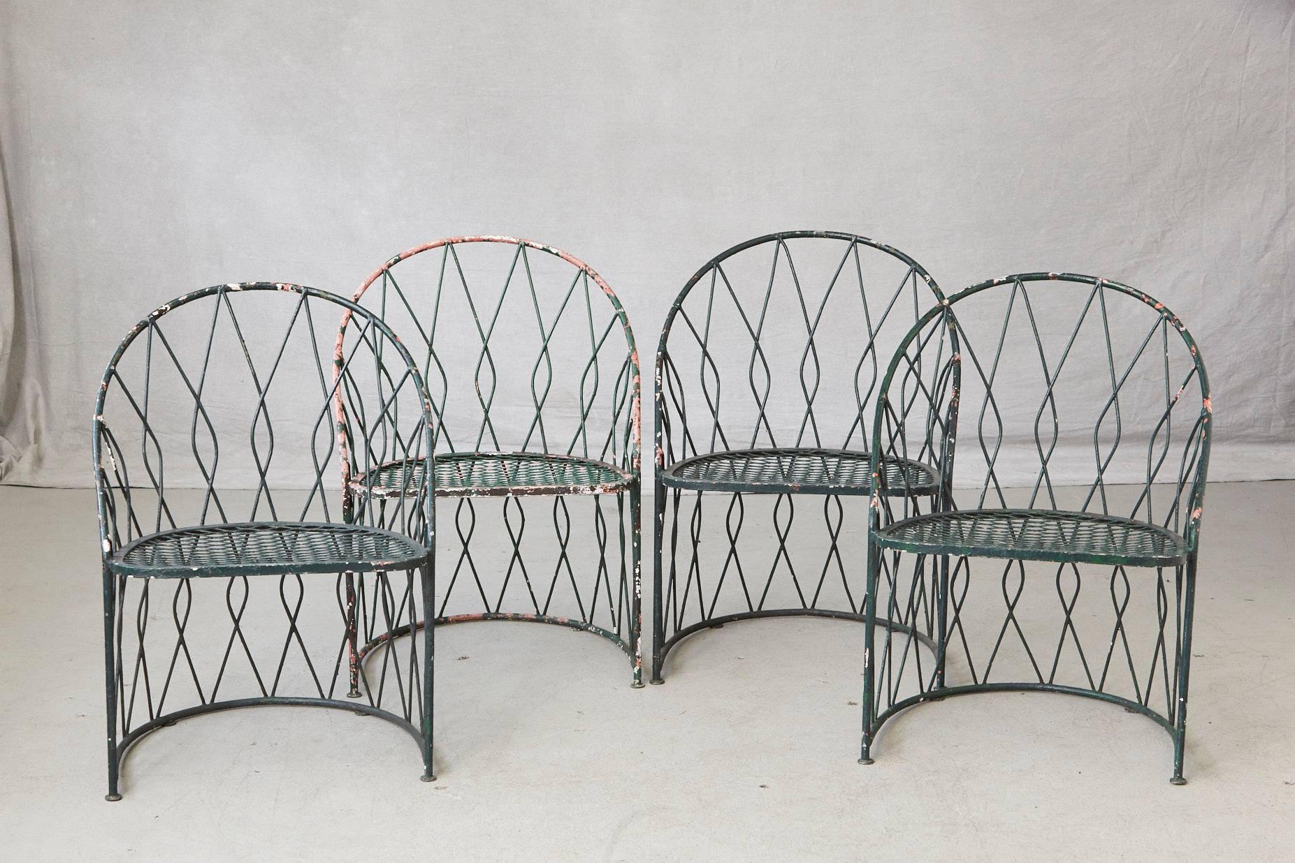 Rare set of four dark green round wrought iron garden or patio chairs by Salterini.
The chairs are decorated with a graphical, scrolled round iron backrest, very sturdy.
The green 'turtle' cushion seats are in good condition, both foam and fabric.