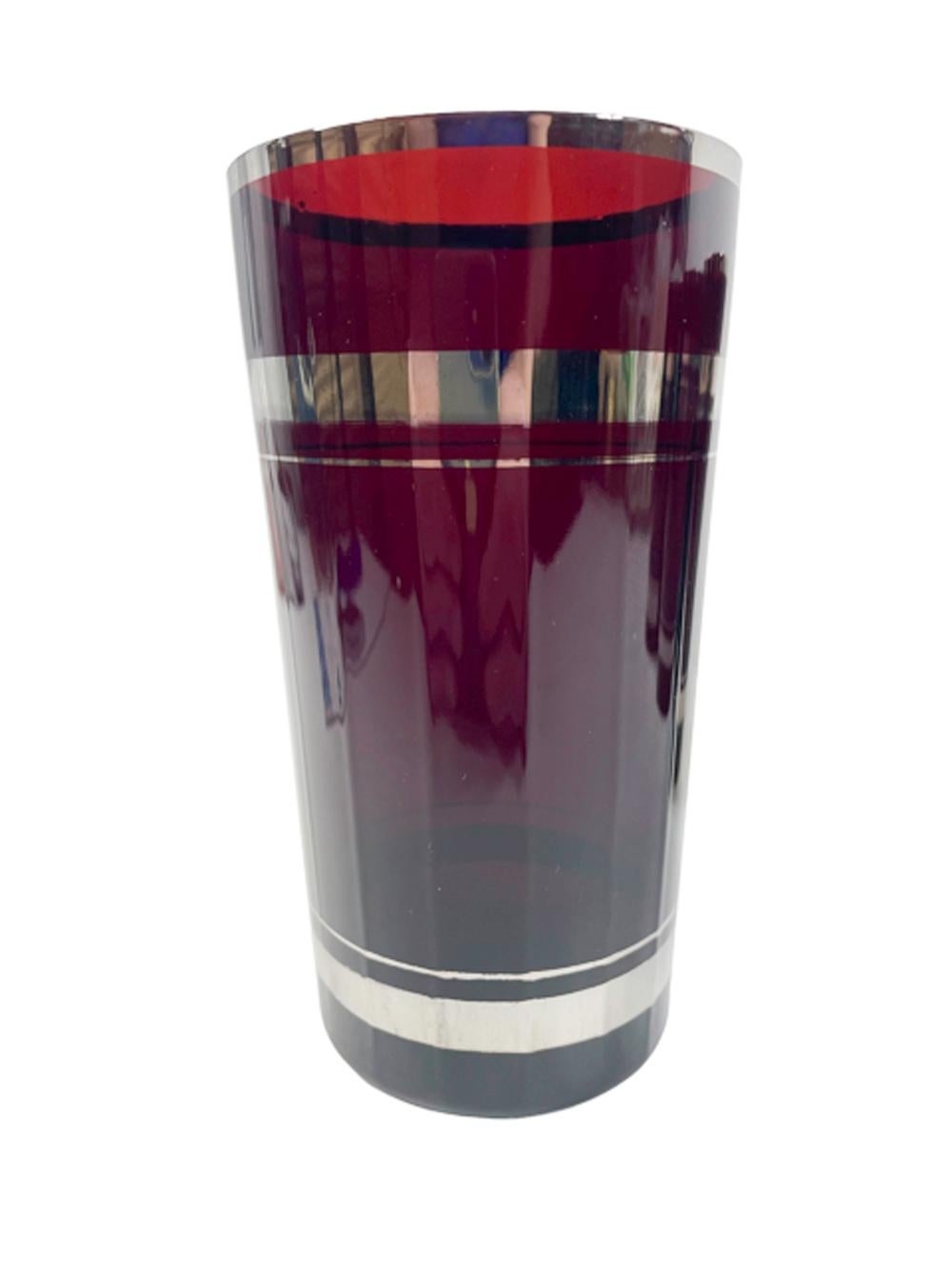 Set of four highball glasses in ruby red glass having multi-faceted paneled sides with silver bands.