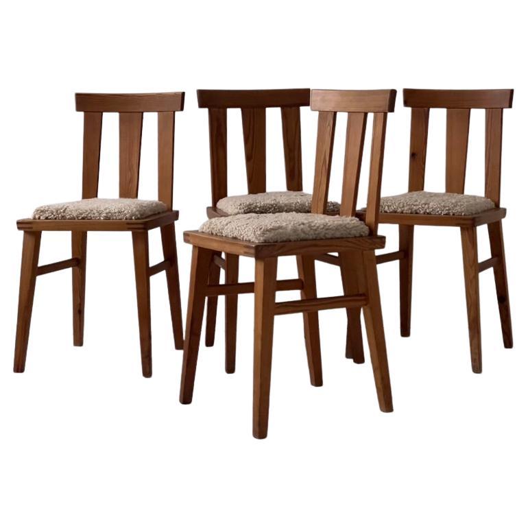 A set for 4 beautifully aged scandinavian pine chairs with a elegant deep golden color. New natural sheepskin upholstery that has been sewn together from smaller pieces creating a beautiful subtle graphic pattern. In the style of Axel Einar Hjorth