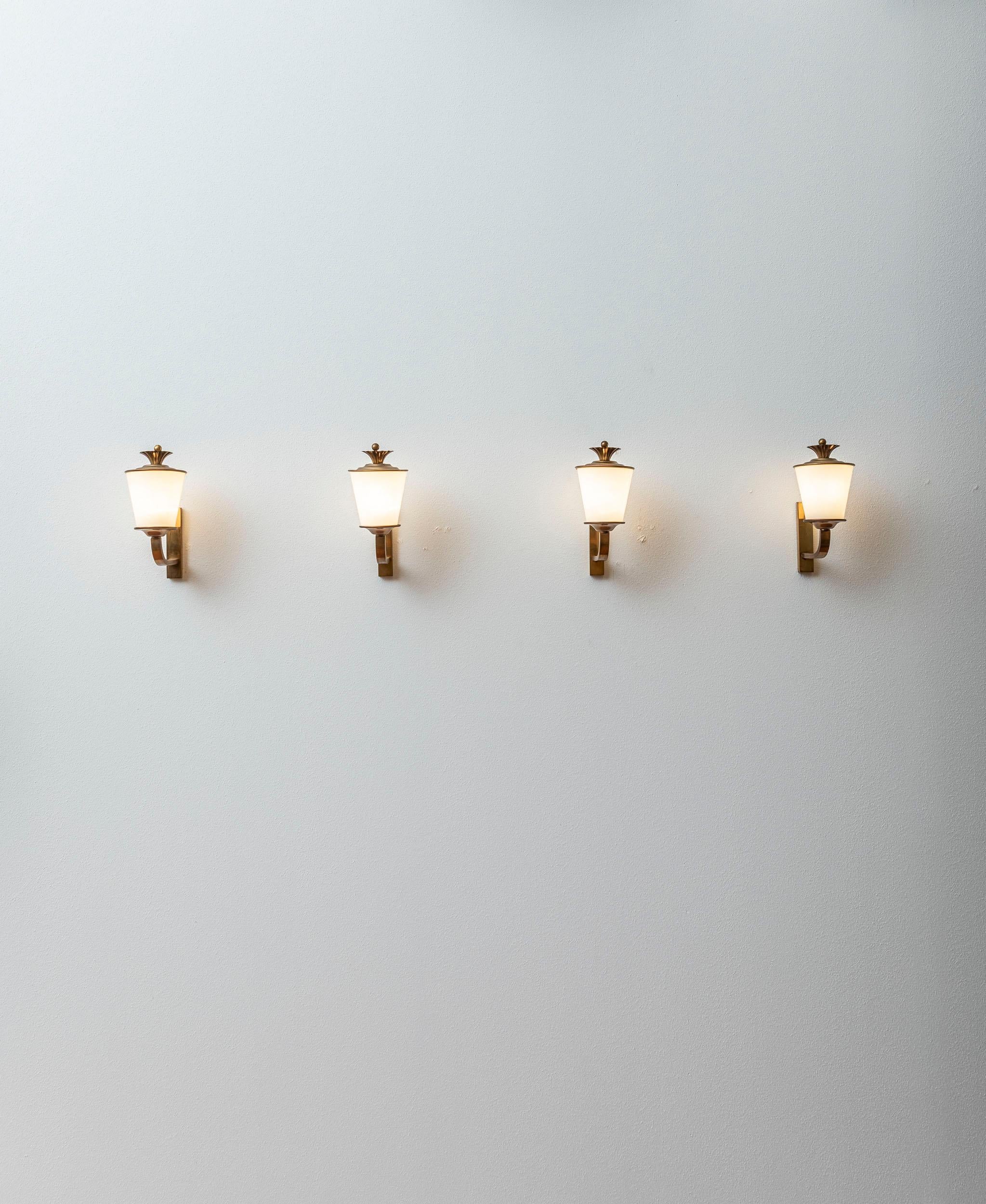 Opaline glass and brass wall lights attributed to Paolo Buffa.
Rare set of four sconces, elegant and charming items.
The brass details on the heads of the opaline shades give a glamorous touch of elegance.