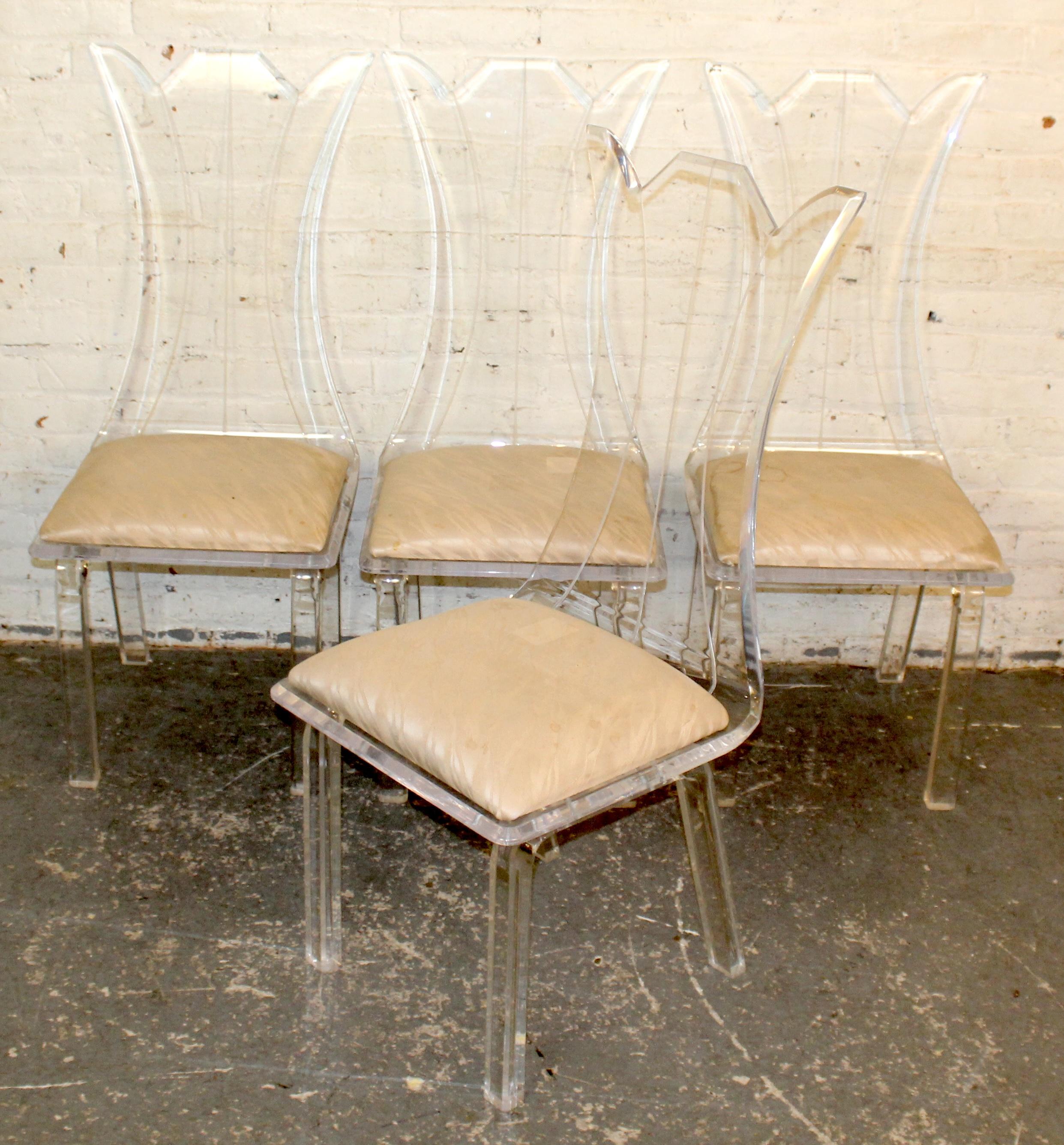 Lot de quatre chaises de salle à manger vintage en Lucite, avec d'élégants et sculpturaux dossiers hauts et des cadres en acrylique transparent qui captent et reflètent magnifiquement la lumière. Les coussins d'assise originaux et touffus offrent un