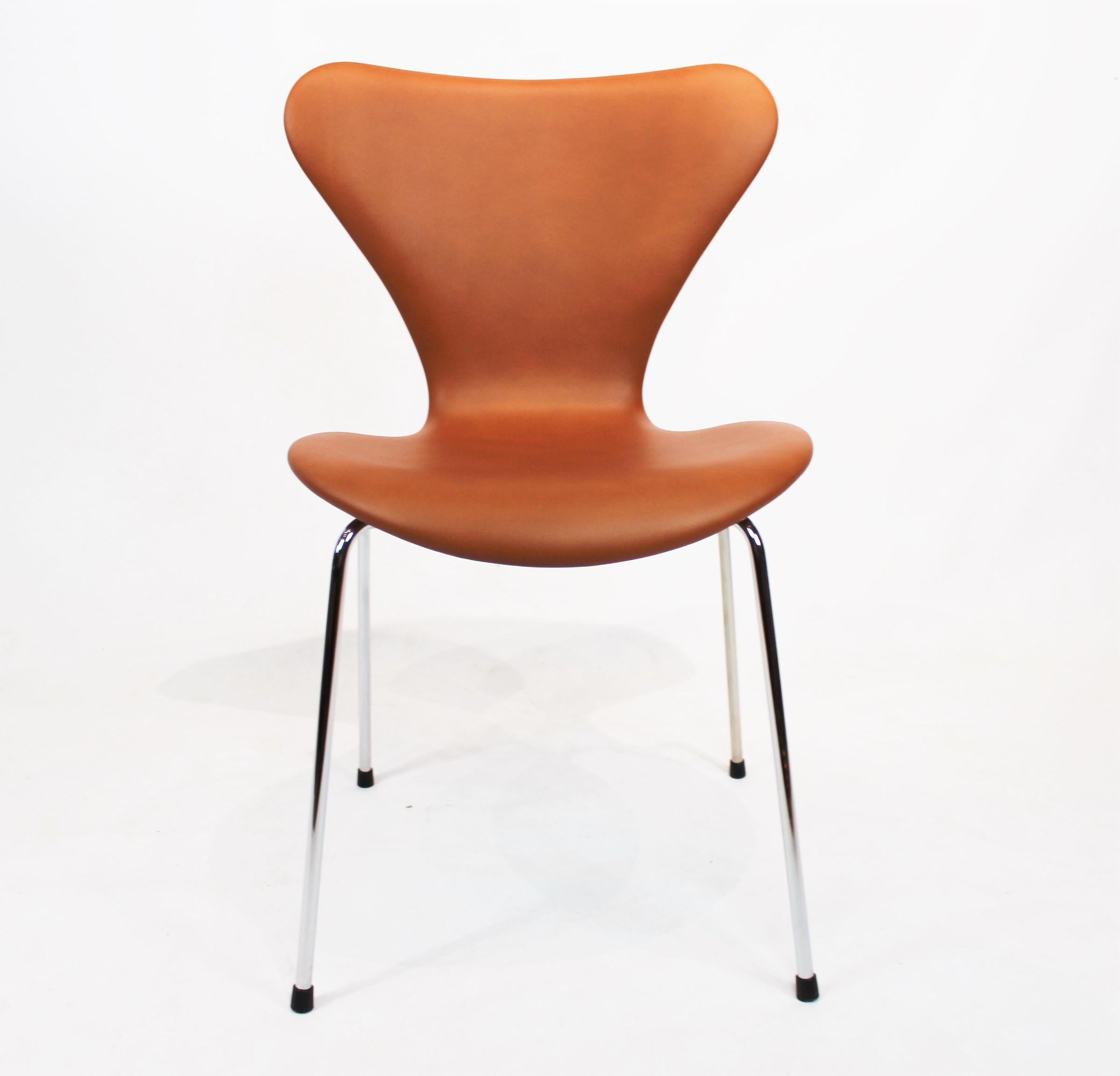 Exquisiter Satz von vier Stühlen der Serie Seven, Modell 3107, umhüllt von luxuriösem Cognac-Leder, ein Zeugnis für Arne Jacobsens visionäres Design.

Diese Stühle, eine klassische Manifestation von Arne Jacobsens ikonischem Design der Serie Seven,