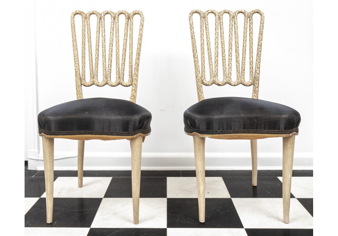 Ensemble de quatre chaises de salle à manger sophistiquées avec un dossier en forme de gribouillis décoré dans une finition gesso avec des vignes feuillues peintes à la main. L'assise en forme de cœur est recouverte d'un tissu très fin, semblable à