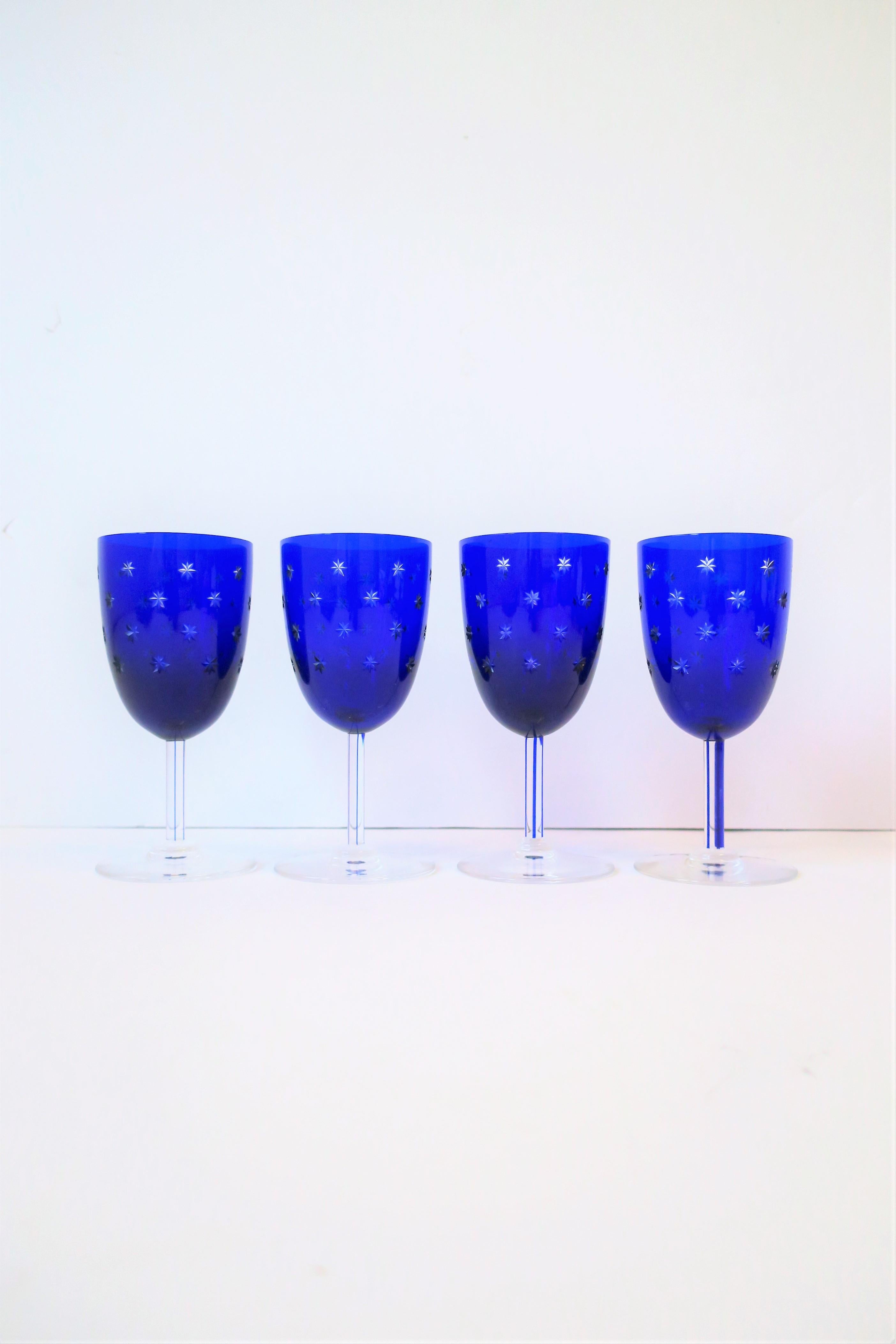 A gorgeous and substantial set of four (4) cobalt blue and clear glasses from luxury crystal maker Saint-Louis, circa 20th century, France. Crystal is clear and royal/cobalt blue with a 'cut to clear' star design (see image #9.) With marker's mark
