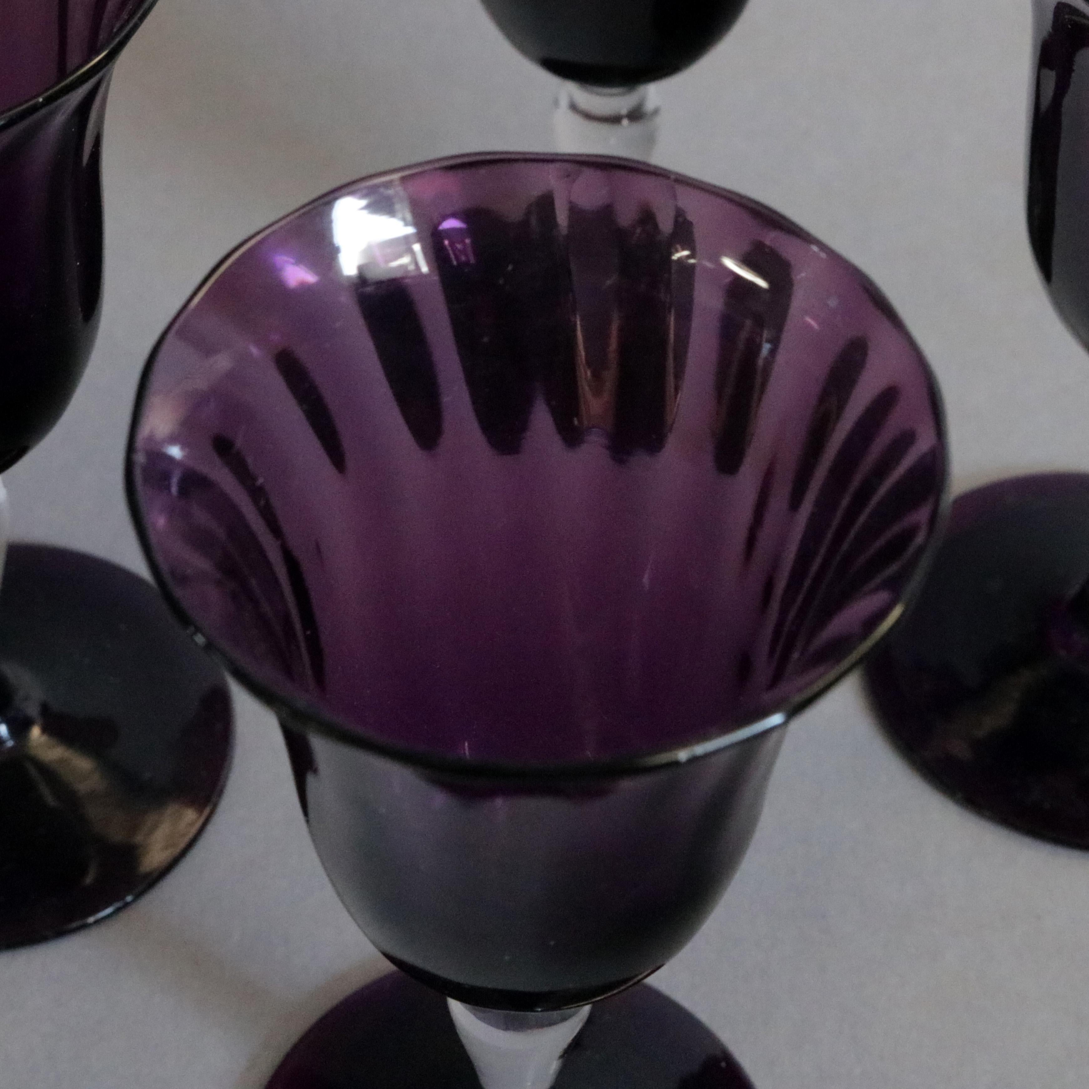A set of four stemmed cordials by Steuben offer flared amethyst art glass cups and feet with colorless glass stems, 20th century

Measures: 4.75