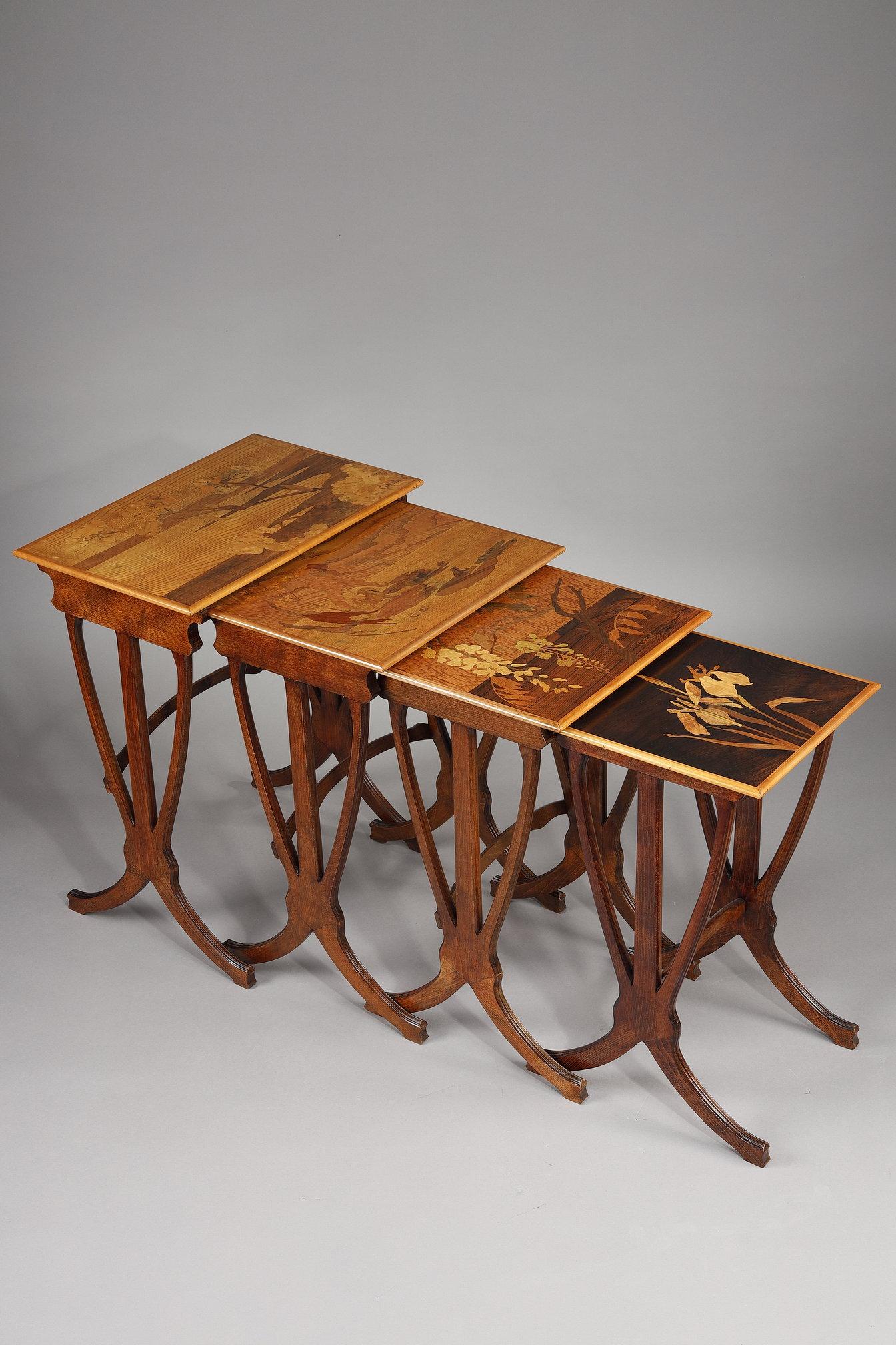 Gallé marquetry nesting tables in different woods, decorated with iris, wisteria, a frog on a water lily and umbellifers, composed of four elements. Signed Gallé.