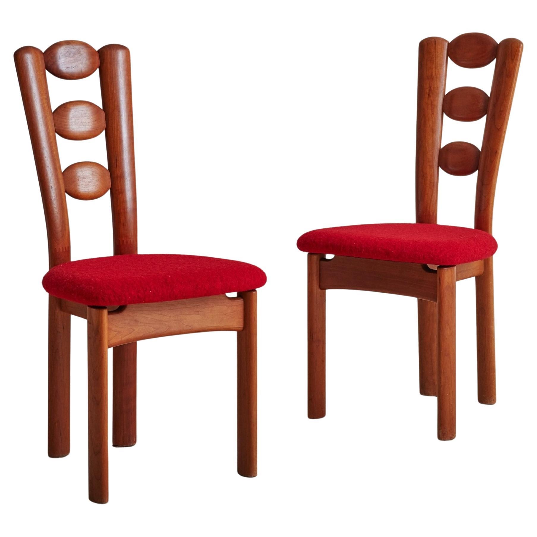 A fabulous set of 4 Danish dining chairs featuring beautifully grained teak wood frames with upholstered seats. The carved back legs of these chairs gracefully extend and arch upwards to frame three floating ovals, which composes the seat back. The