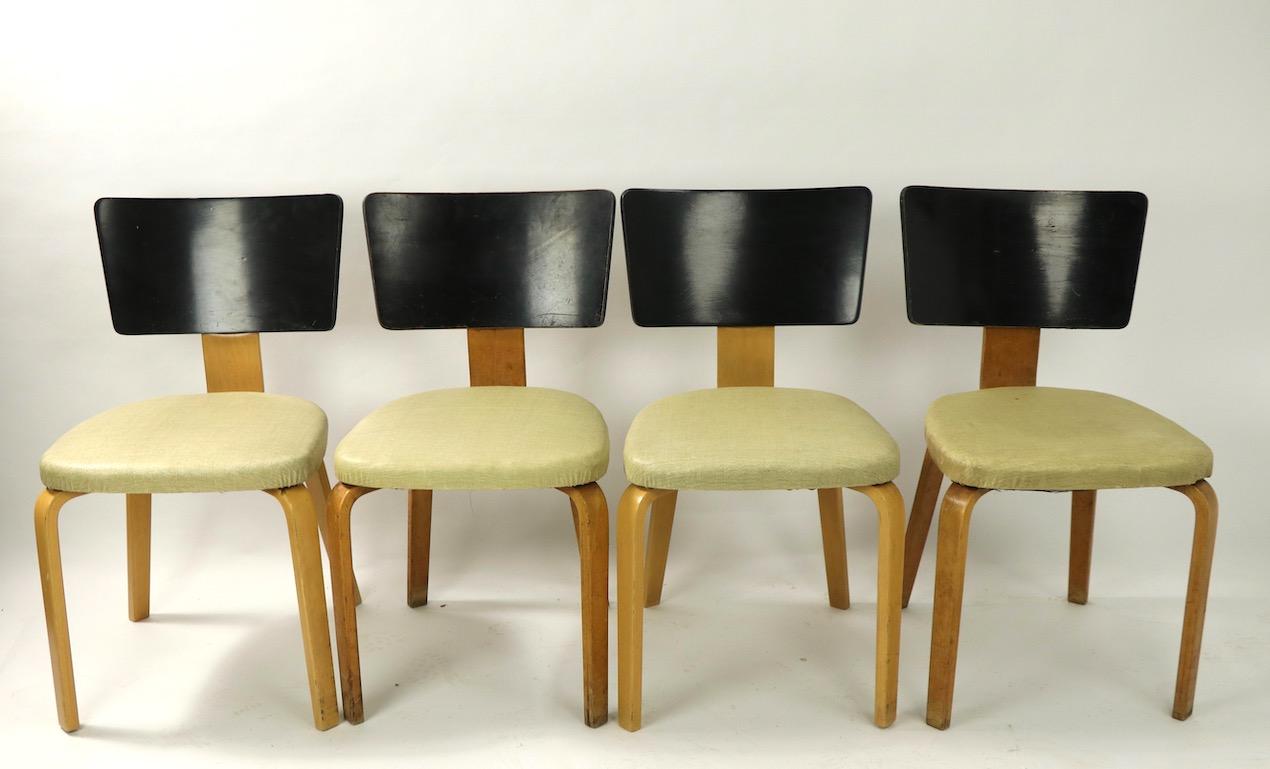 Classic Mid-Century Modern dining chairs by Thonet. The chairs have blonde bent plywood legs and black bent plywood backrests. Two chairs have had the blonde legs refinished, while two remain in the original finish, which shows cosmetic wear normal